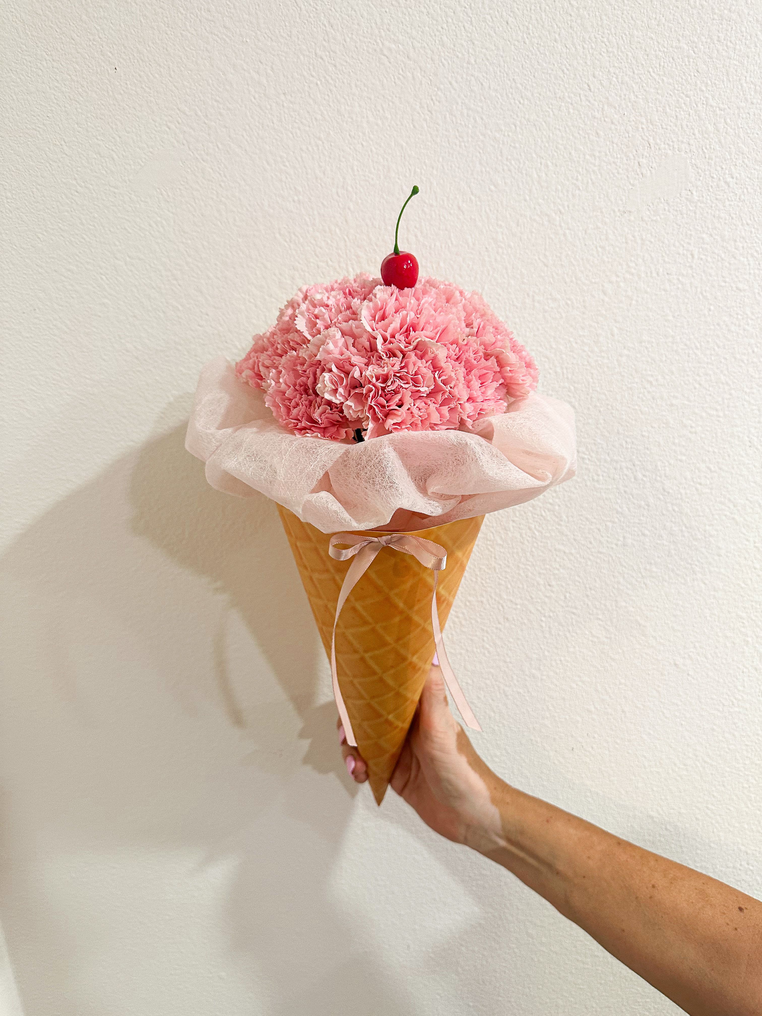 Sweet Blooms Cone - A floral treat almost too cute to handle! This playful ice cream-inspired bouquet comes in a variety of “flavors” (colors!) and is topped with a cherry on top. The perfect gift for birthdays, celebrations, or anyone who deserves a sweet surprise!  SUBSTITUTION POLICY If the exact flowers or container you have selected are not available we will create a beautiful bouquet with the freshest available flowers. We will only substitute items of equal or higher value.