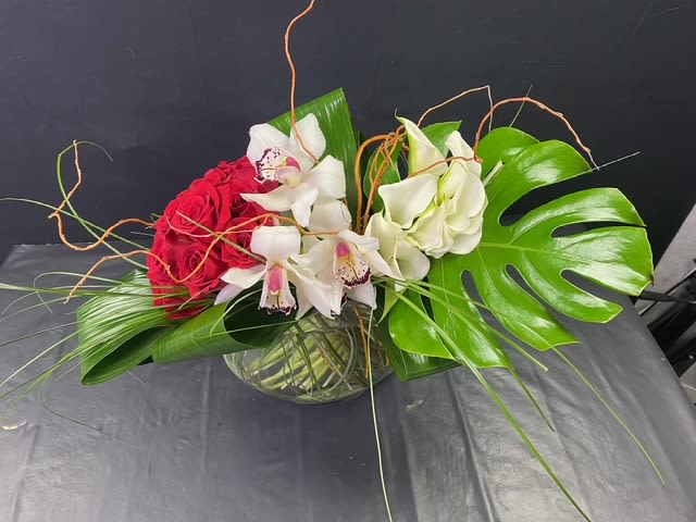 Exotic Beauty Bouquet - This stunning bouquet is full of fresh roses, cymbidiums, and calla lilies. It is handcrafted and designed in a flask container vase with beautiful greenery. It will make your loved one feel so loved and special and makes for a wonderful gift for a very special occasion.