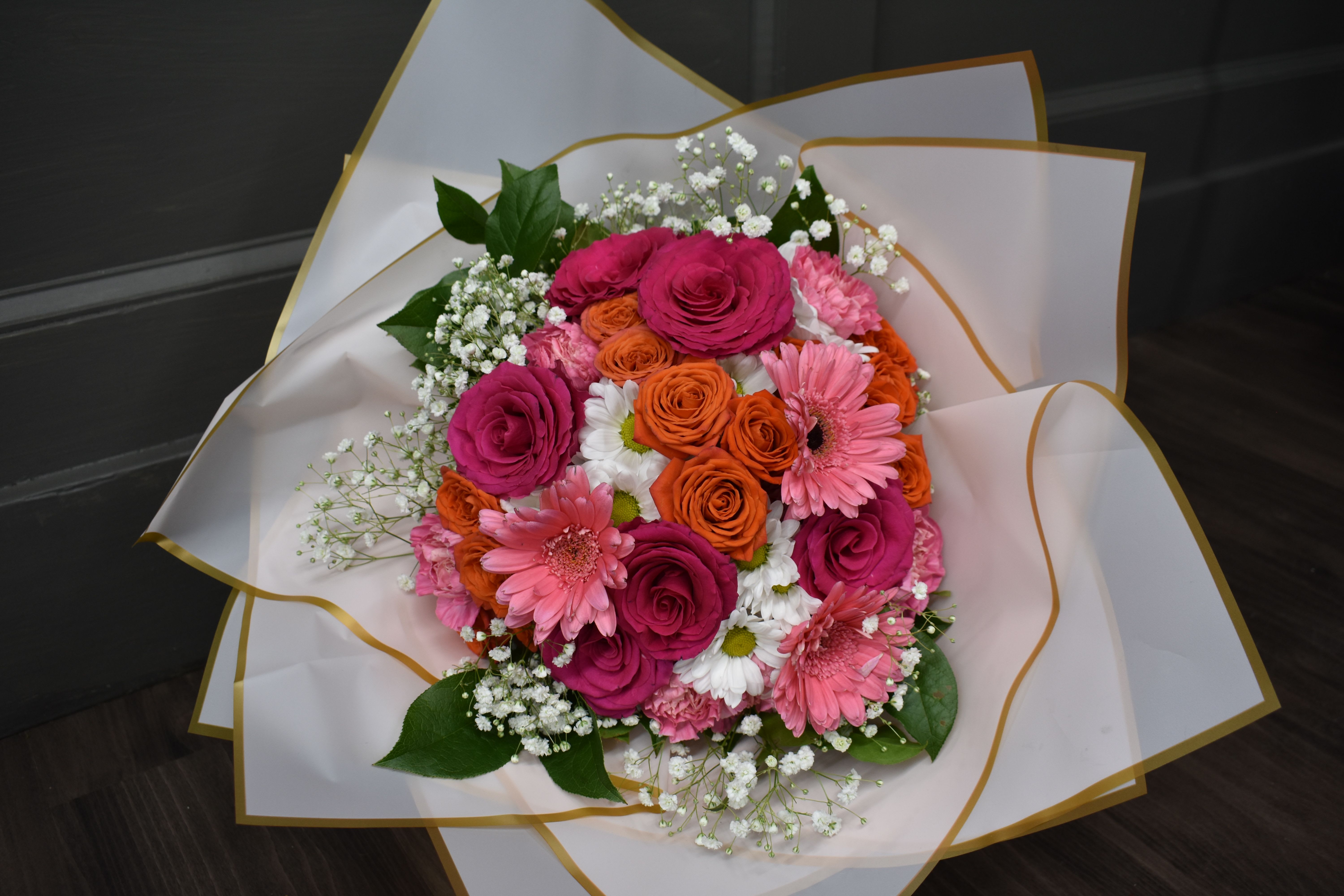 Colorful Fancy Wrap Bouquet - Vase not included  - Have a vase at home or want an extra special display to hand to your Valentine? Our NEW wrapped bouquet might be for you! We grouped some of our favorites, daisies, gerrondo gerbera daisies, spray roses, and roses delicately arranged with fresh greenery and baby's breath, then hand-wrapped in our gold-edged wrapping. These flowers also come wrapped with our Arrive-Alive system that covers and hydrates the stems to make sure they last until you get home. Remember to give them a fresh cut before putting them in a vase and use the flower food packet we send with! ***Colors may vary, we use our best and freshest blooms!