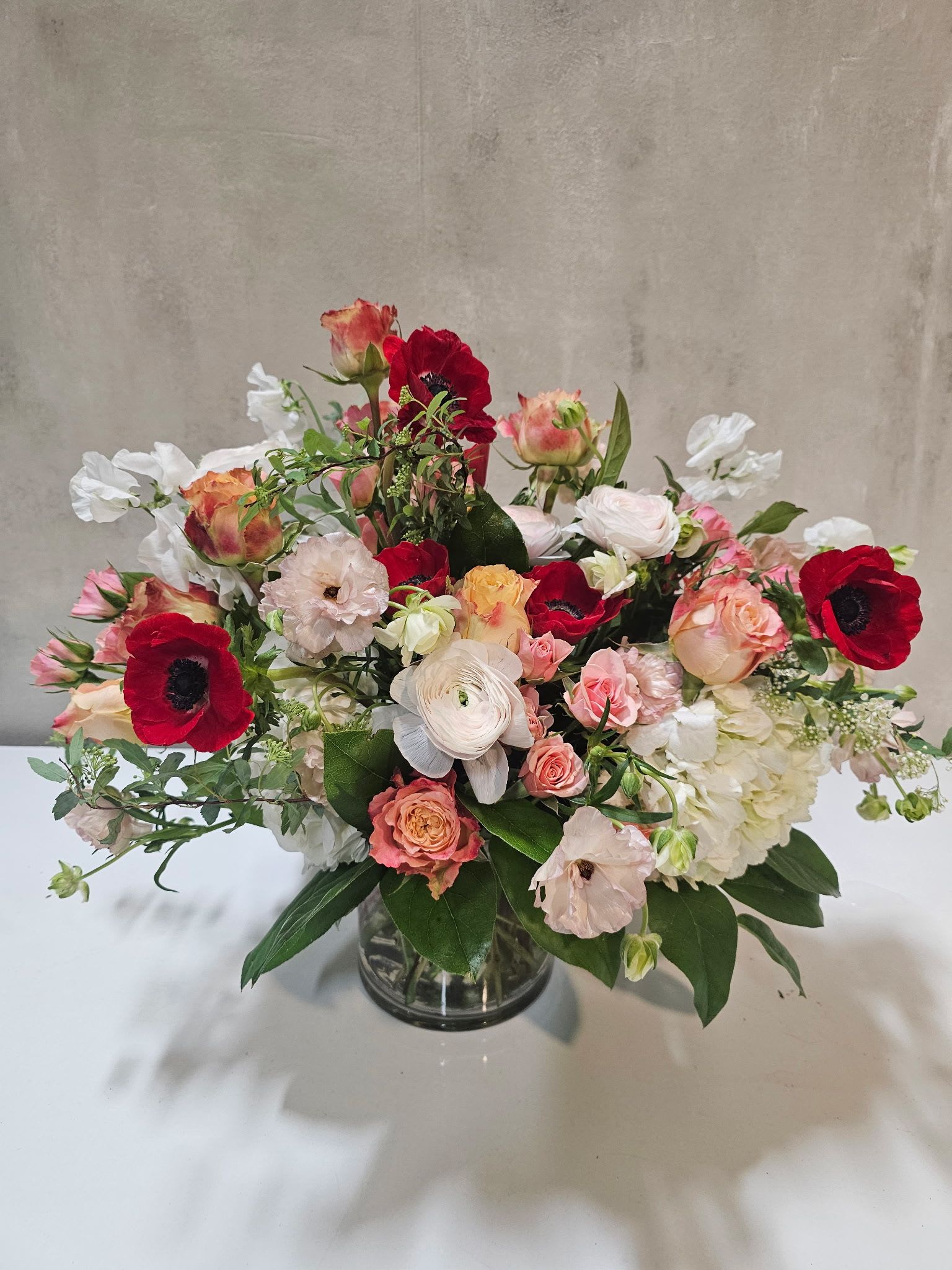 Garden Party Muse - A fresh, garden-inspired arrangement blending romantic roses, delicate ranunculus, airy seasonal blooms, and lush greenery in a naturally styled silhouette. Soft yet vibrant, this design feels like springtime elegance gathered straight from a blooming garden.