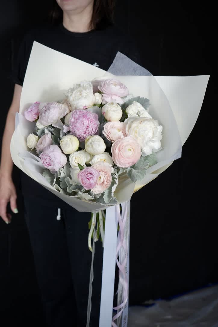 Whispering Elegance Bouquet - The Whispering Elegance Bouquet is a stunning arrangement that radiates sophistication and grace. This bouquet features an exquisite mix of white and light pink flowers, including peonies and ranunculus, accented with soft, velvety dusty miller foliage. Wrapped in luxurious white and beige paper, it is the perfect gift for expressing heartfelt emotions, celebrating special occasions, or adding a touch of elegance to any setting. The Whispering Elegance Bouquet, adorned with delicate ribbons, is a beautiful and thoughtful gesture that will leave a lasting impression on anyone who receives it.