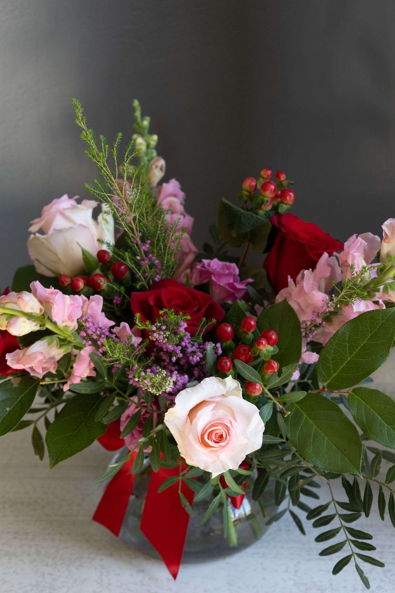 Pink Berry - A Sweet mix of pink, red and lavender roses, berries, snapdragons and fluffy greens in glass vase  stands about 14" tall and 12" wide