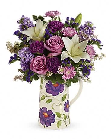 Teleflora's Garden Pitcher Bouquet - A Mother's love grows as bright and beautiful as a garden! Honor her unwavering devotion this Mother's Day with this 2-in-1 gift: a luxurious mix of lavender roses and pure white lilies, hand-delivered in a charmingly rustic, Provencal style ceramic pitcher that's food safe for years of happy pouring! This garden-inspired bouquet features lavender roses, white asiatic lilies, purple carnations, lavender stock, lavender cushion spray chrysanthemums, lavender sinuata statice, seeded eucalyptus and variegated pittosporum. Delivered in a Garden Pitcher.