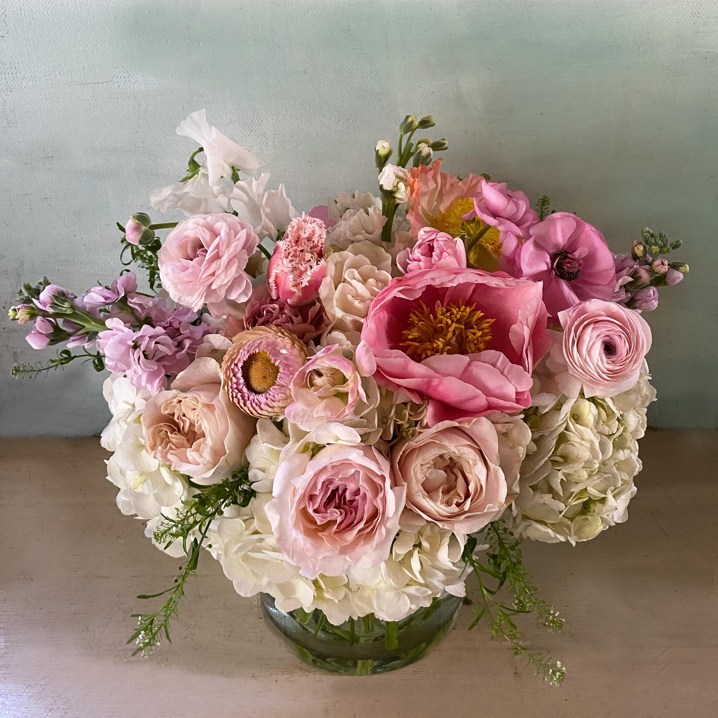 Paula Peony arrangement - A medium sized beautiful arrangement placed in a 5" by 5" vase, full of lovely, feminine colors of love, perfect for VAlentines Day, your lovely Mother or any romantic occasion. Roses and peonies, the preferred stems of so many, adorn this pretty arrangement along with seasonal fresh stems in pastel colors. If peonies are not available, beautiful ranunculus or dahlias or poppies will be used. Choose Deluxe for a fuller and larger arrangement with more flowers. Choose premium for the x-l version of the arrangement with even more flowers. Blomst LA only uses fresh, high quality flowers, all carefully selected every day to fit your flower order. We offer a personal hand delivery by our own delivery staff and guarantee the flowers will look perfect, when they arrive. We deliver in Glendale, Pasadena, Eagle Rock, Hollywood, Burbank, Beverly Hills and - and everywhere else in Greater Los Angeles.