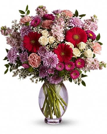 Teleflora's Perfectly Pleasing Pinks - A perfectly pleasing mix of sweet springtime blossoms make this a truly happy gift. So full of feminine flowers and fun feelings, this is the perfect arrangement to make her smile. Dazzling white spray roses, hot pink gerberas and matsumoto asters, pink carnations, lavender cushion mums, light pink stock and much more fill a lavender Inspiration vase.