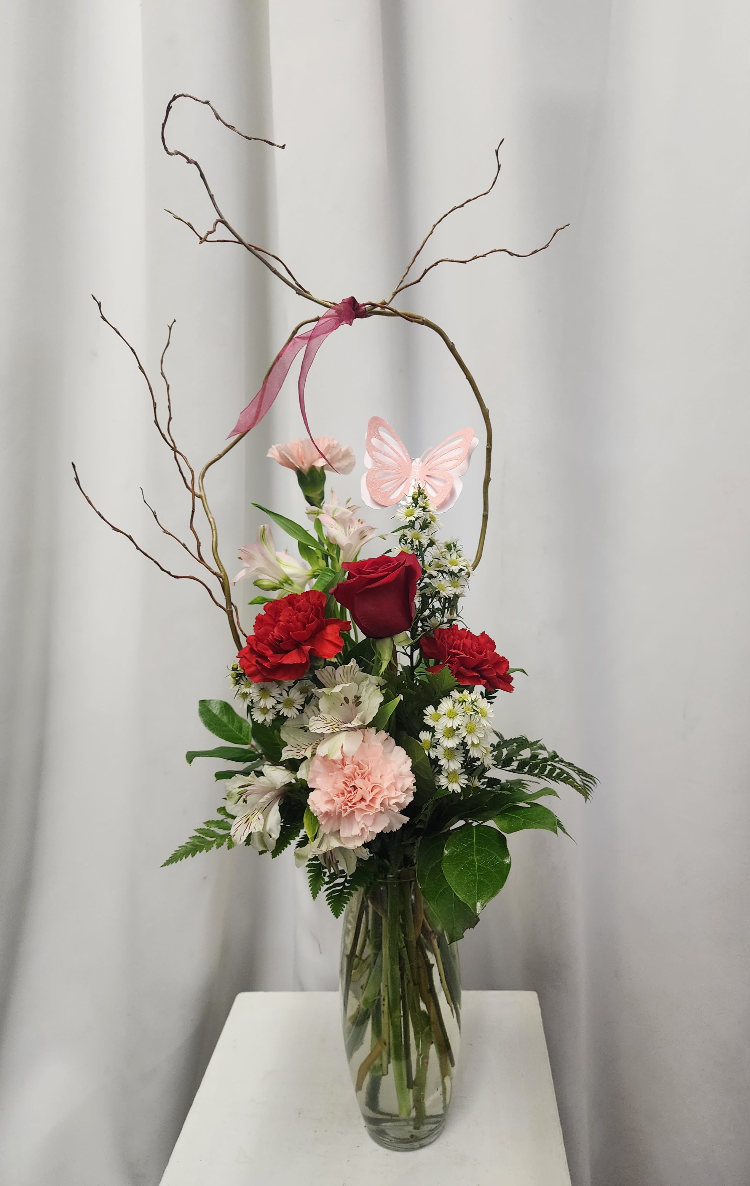 Butterfly Blooms - Red and pink flowers in a tall vase, accented with curly willow and a handmade butterfly for a whimsical touch.  Simple, fun and beautiful all in one.