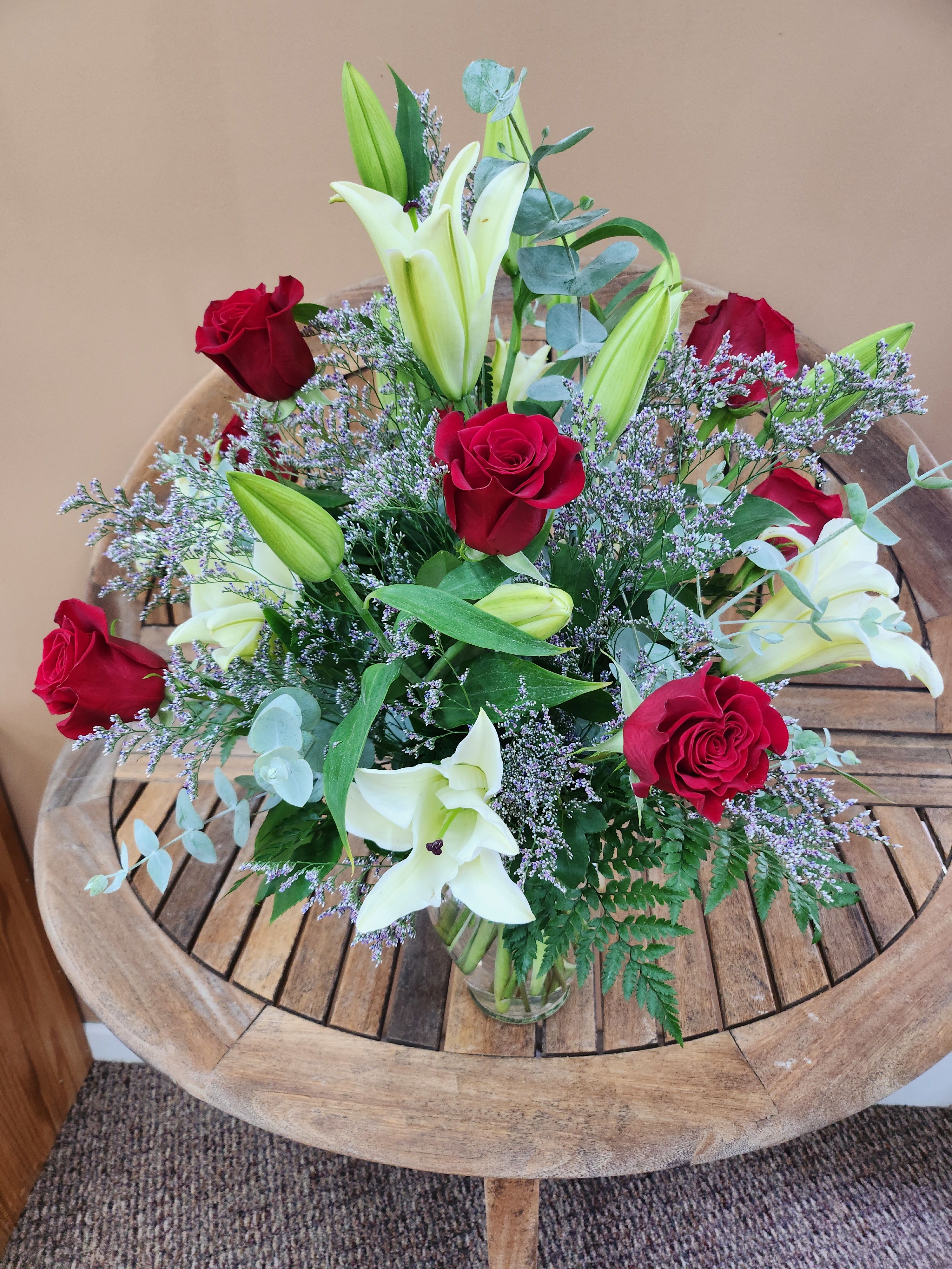 Red Roses And White Lilies - A mixture of red roses and white lilies with fifiller and greens in a clear glass vase.