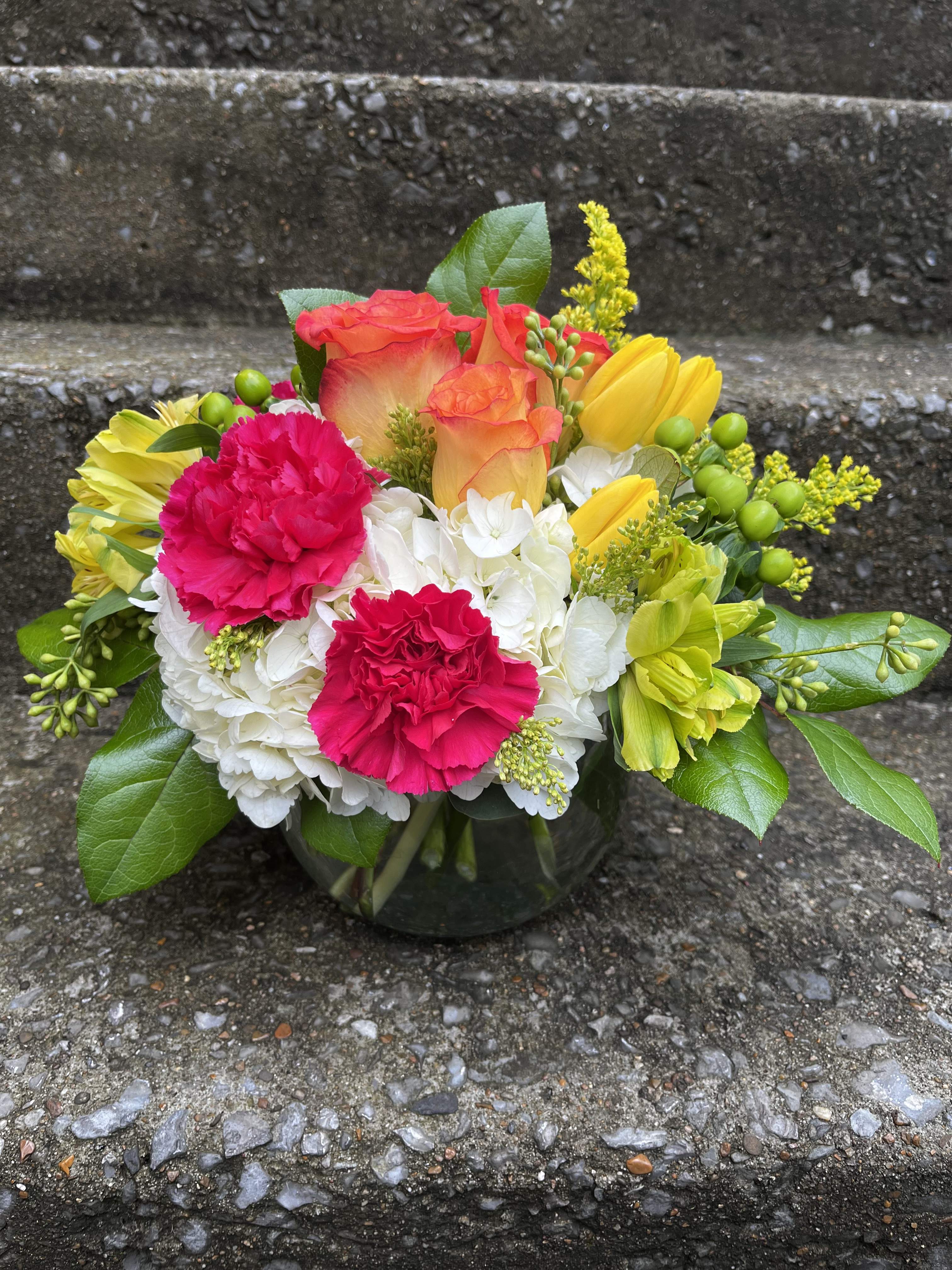 Paradise  - This arrangement has hydrangea, orange roses, yellow tulips, yellow alstroemeria, hot pink carnations, green Hypericum, Solidago, and beautiful greenery
