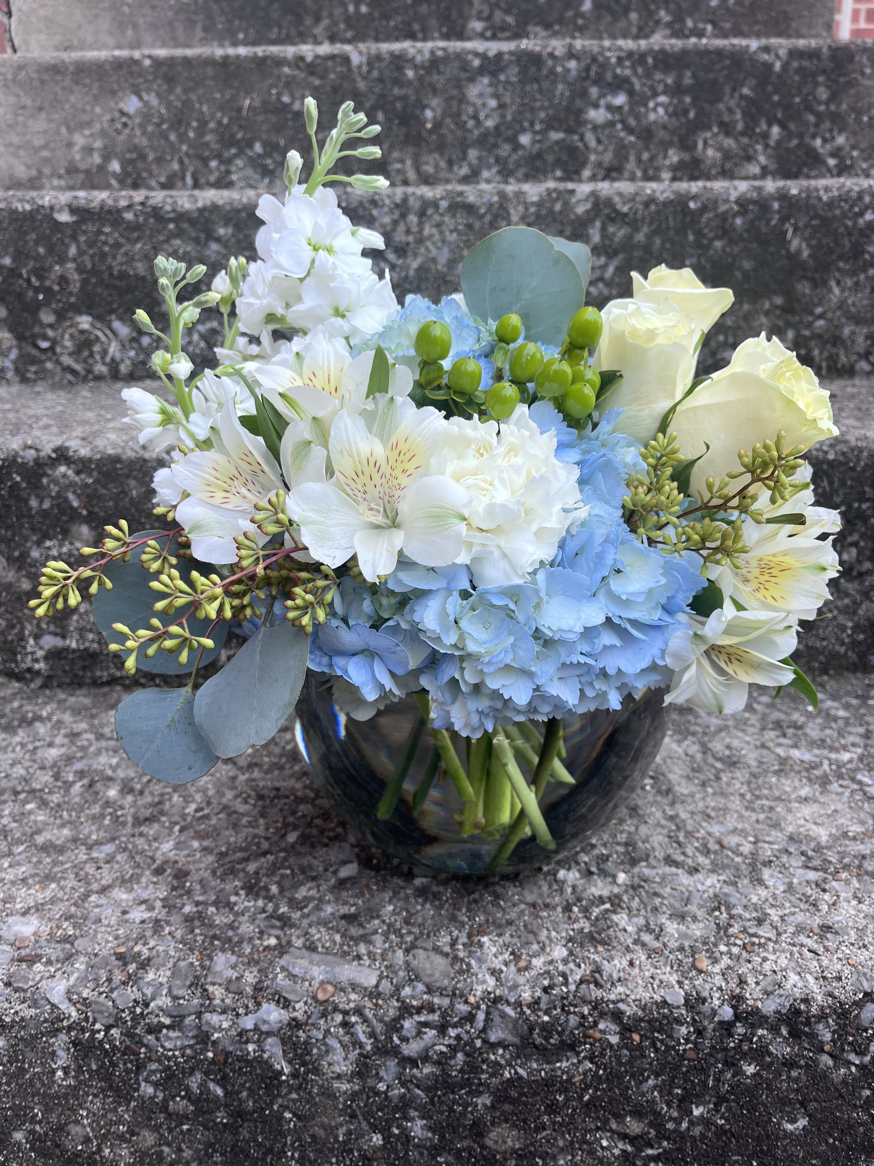 Pure Liberty - This arrangement has blue hydrangea, white carnations, white alstroemeria, green Hypericum, white roses, white stock and beautiful greenery.