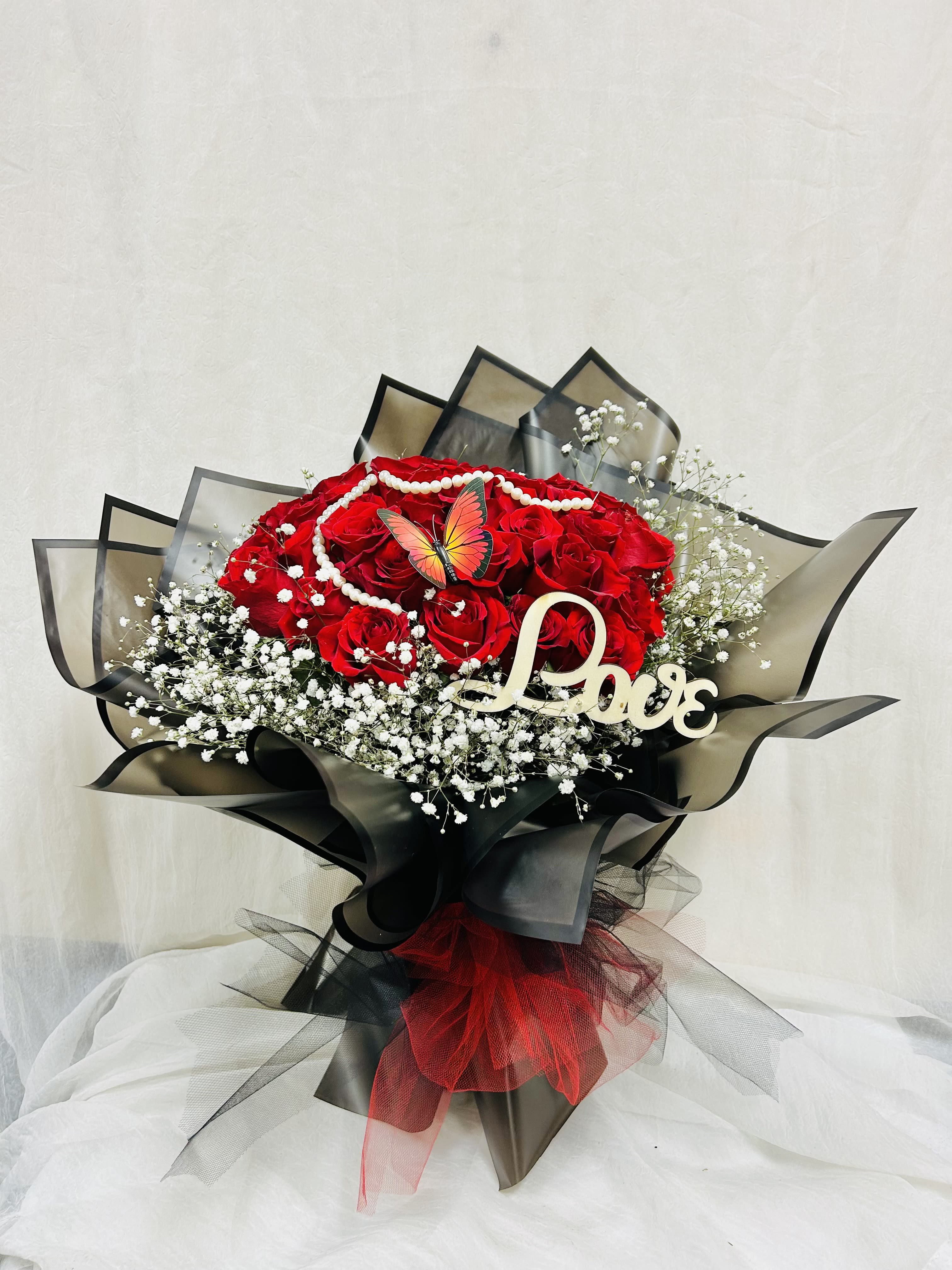 Red rose bouquet with baby's breath, pearl garland, and a Love sign