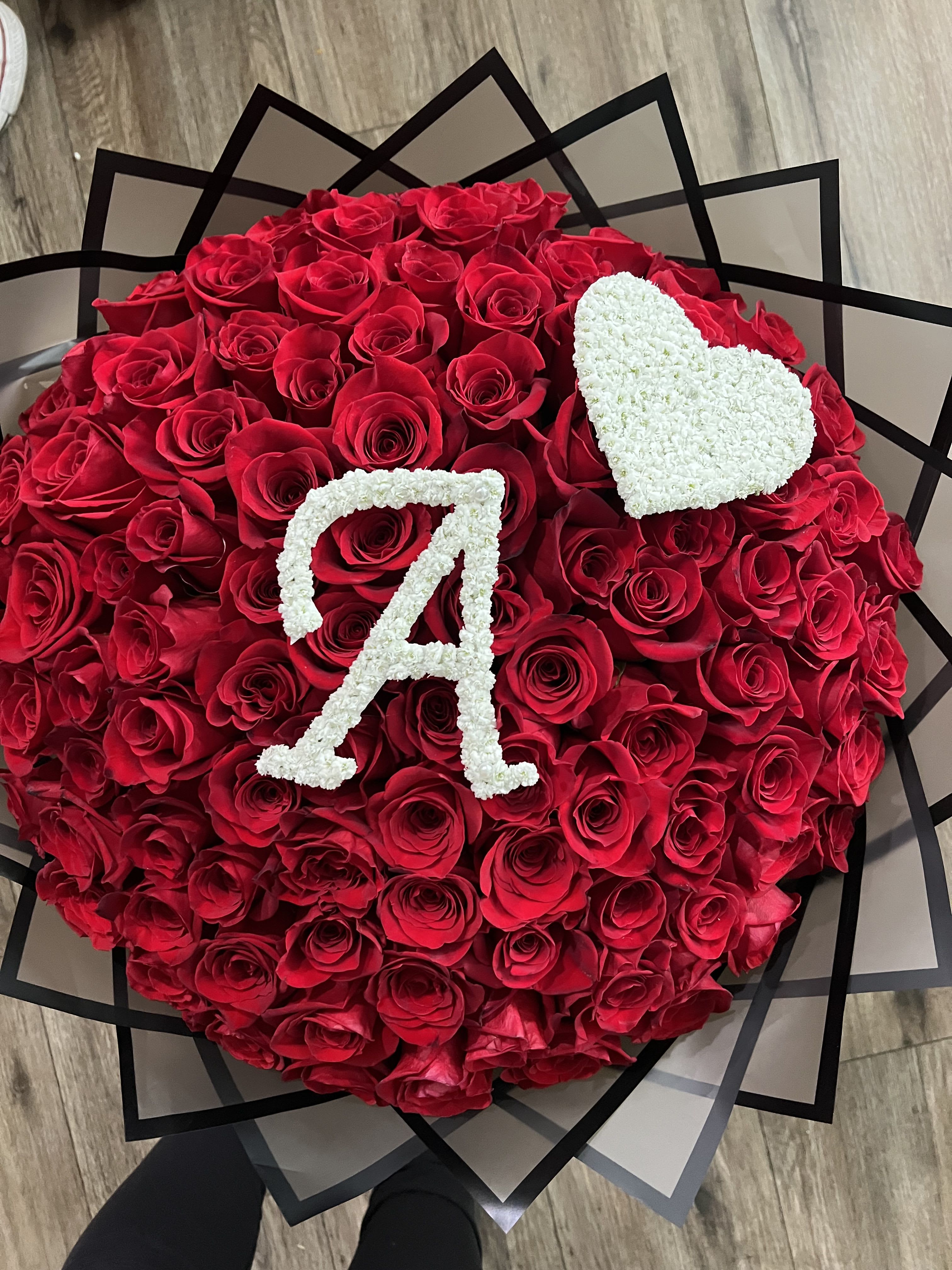 Red Rose Floral Bouquet Bouchón with Custom Details - Make a lasting impression with this breathtaking floral arrangement featuring premium red roses, artfully designed for a rich and romantic look. A delicate white heart made of fresh flowers adds heartfelt beauty, while personalized lettering makes it perfect for quinceañeras, weddings, or memorial tributes. 