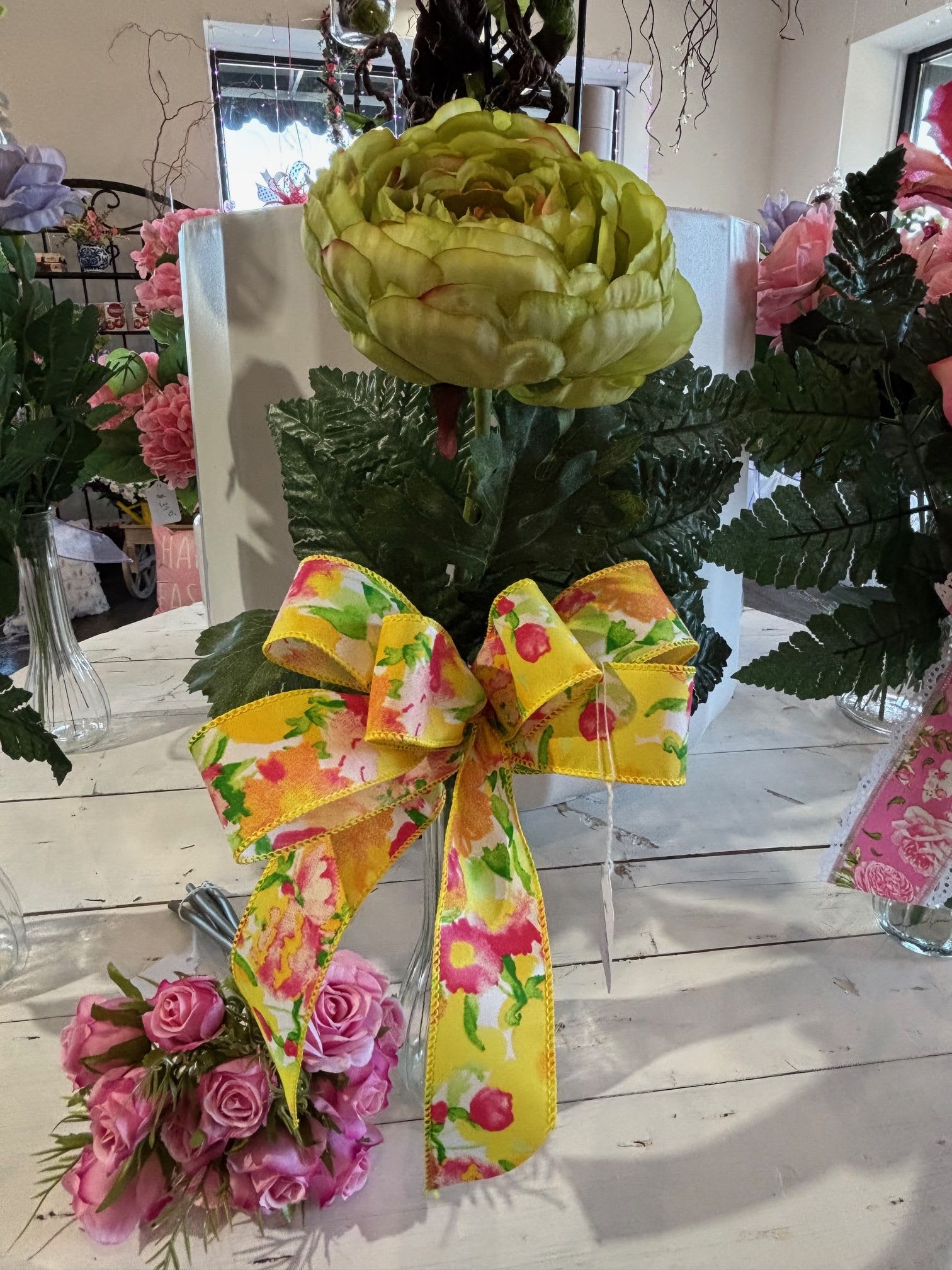 Green Artificial Garden rose budvase with a bright festive bow - An artificial vibrant green garden rose in a bud vase with a festive bow, adding a fun and elegant pop of color.