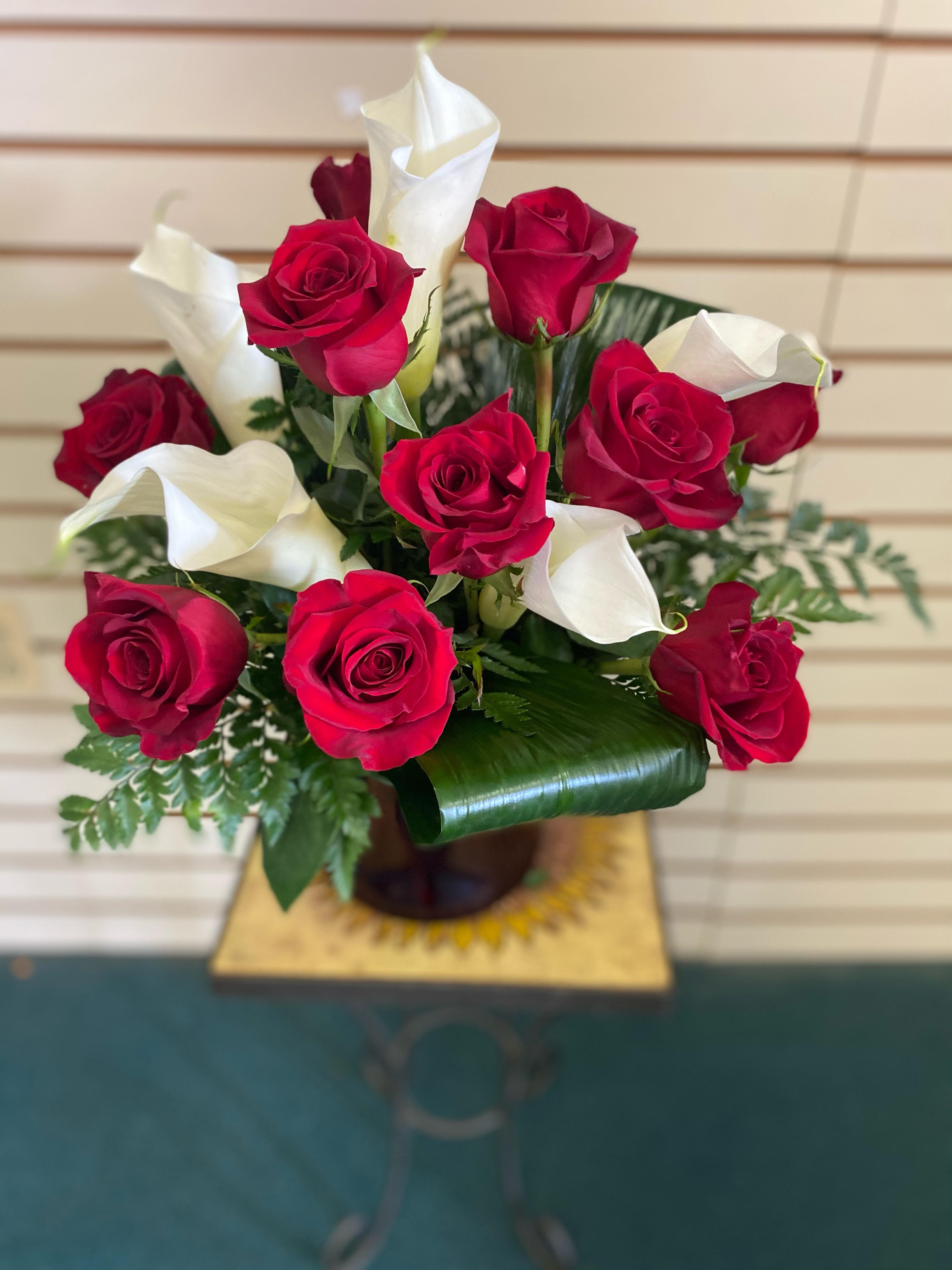 Be Still My Heart - Dozen Red Roses with callas  - The look of love is charmingly reflected in this romantic array of red roses and fragrant white callas. Beautifully presented in a sparkling glass vase, these gorgeous flowers will say what's in your heart more eloquently than words.  Regular one dozen red roses and a five white calla lilies accented with assorted greenery. Deluxe  one and half dozen red roses and a five white calla lilies with assorted greenery. Premium  two dozen  roses and a five white calla lilies with assorted greenery.