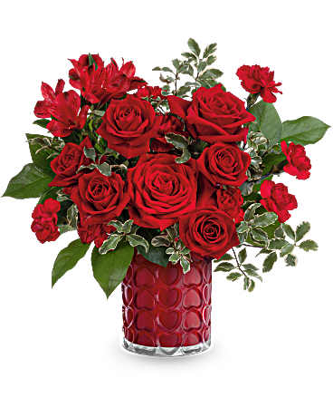 Teleflora's Radiant Hearts Bouquet - As radiant as your love, this romantic Valentine's Day bouquet shines beautifully in a pearlescent vase adorned with an embossed heart pattern. This Valentine's Day bouquet showcases red roses, red spray roses, red alstroemeria, and miniature red carnations, complemented by lemon leaf and pitta negra. Delivered in the Enchanted Hearts vase.