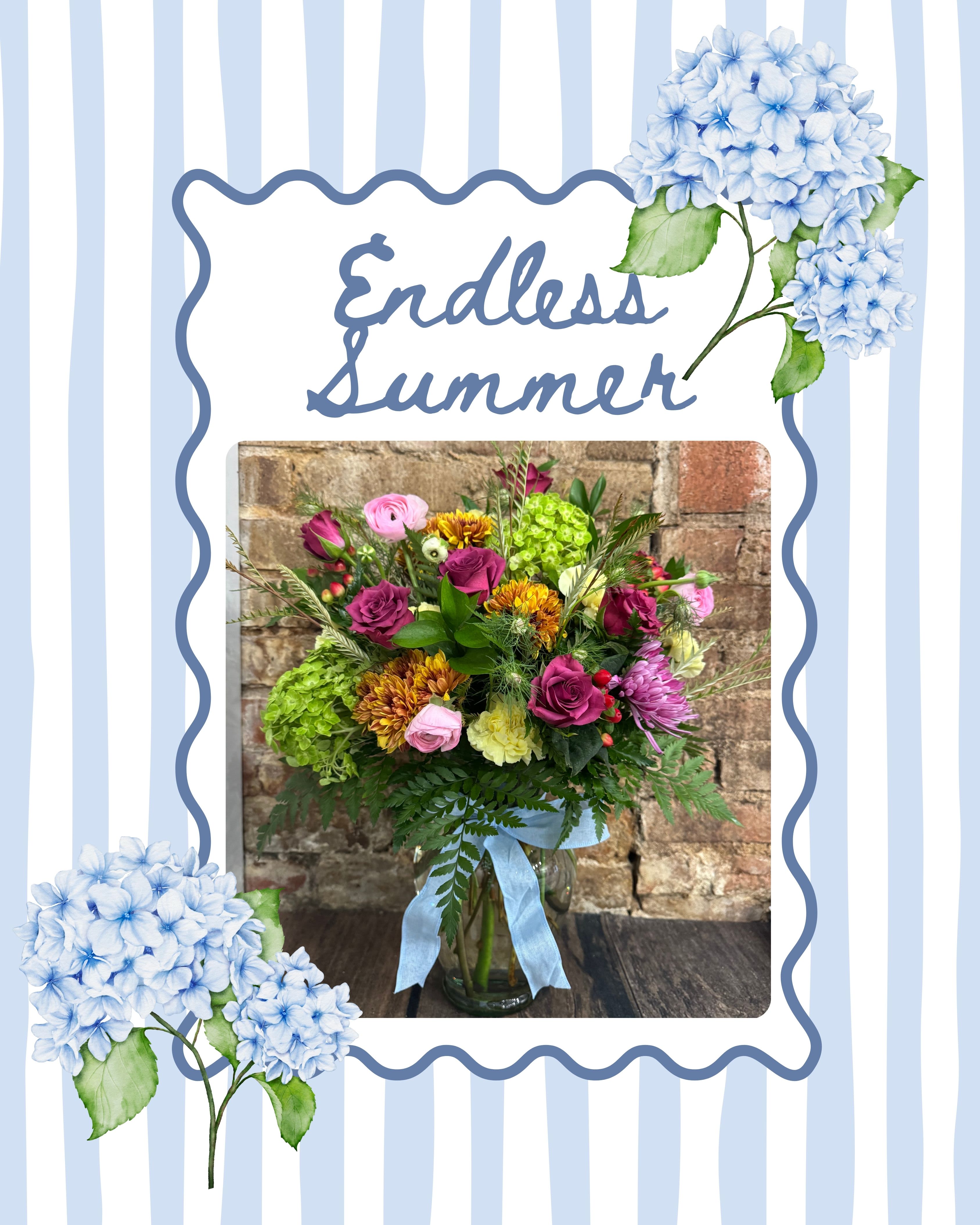 Endless Summer - Our Endless Summer arrangement features a vibrant mix of premium seasonal blooms in soft blues, greens, pinks, and warm summer tones, designed in a clear glass vase and finished with a delicate blue ribbon.