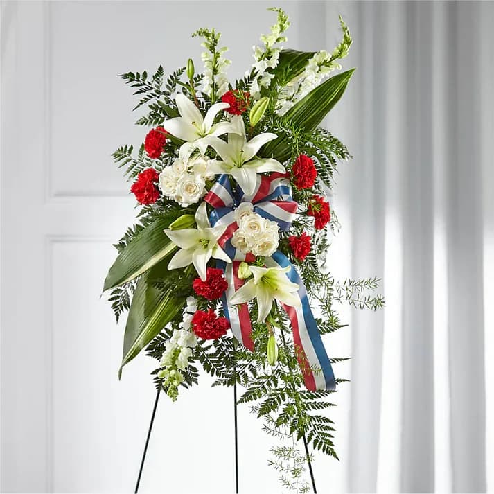 Stars of Life Standing Spray - Share your respects with flowers that evoke the true spirit of a hero. Our Stars of Life spray is accented with a patriotic ribbon and features a gorgeous yet timeless collection of carnations, snapdragons, lilies and roses.  Details 38"h x 19"w