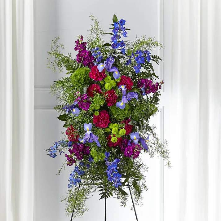Heavenly Skies Standing Spray - This colorful spray is a modern and refreshing mix that brings serenity to those who experience a loss. Our Heavenly Skies Standing Spray is crafted with a beautiful blend of stock, iris, dianthus and delphinium reminiscent of a hopeful wildflower garden.  Details 35"h x 21"w