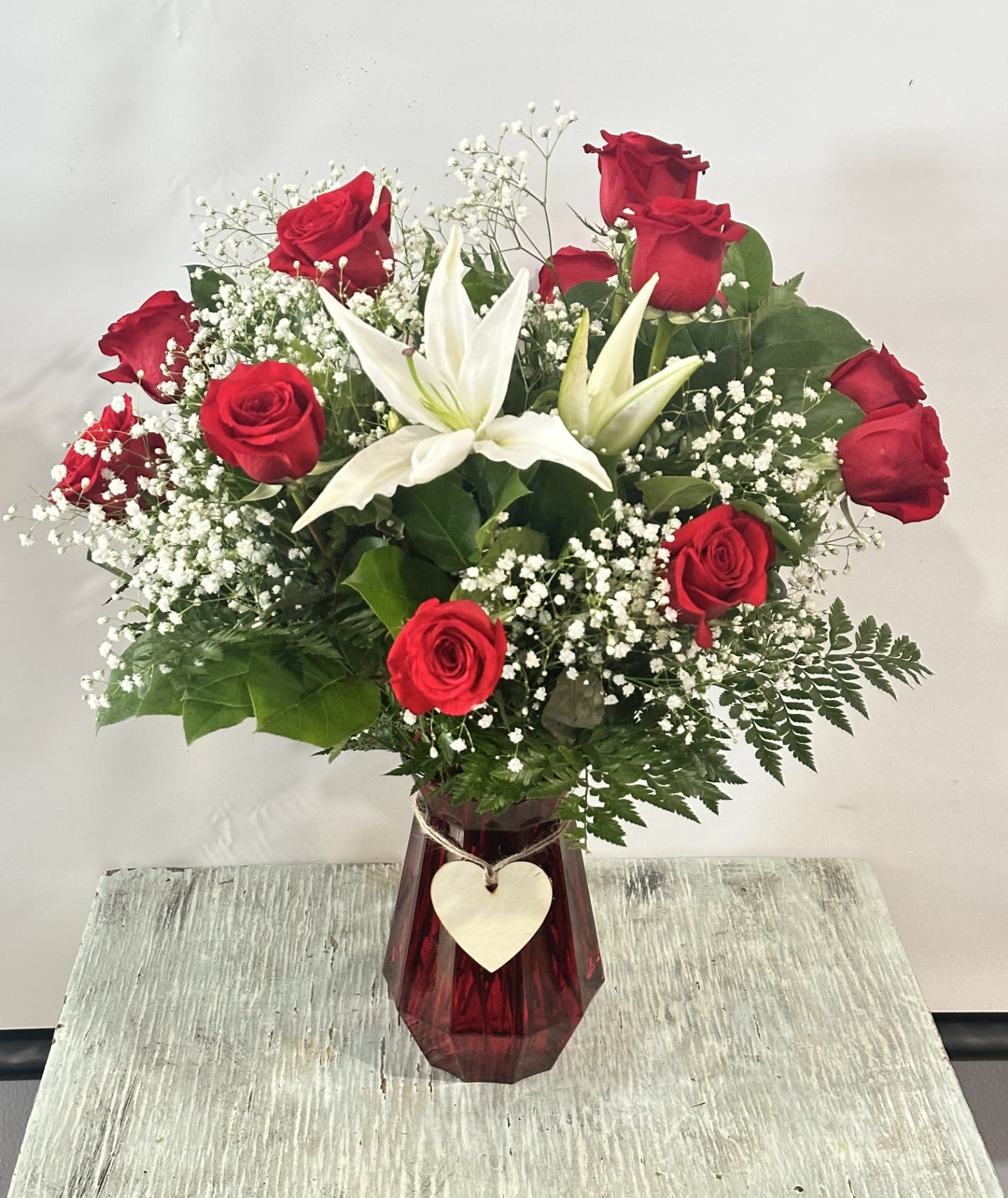 Love &amp; Romance #16 - Arrangement of 1 dozen red roses designed in a ruby red glass vase. Vase embellished with a wooden heart. Arrangement measures approximately 24" tall &amp; 20" Wide.