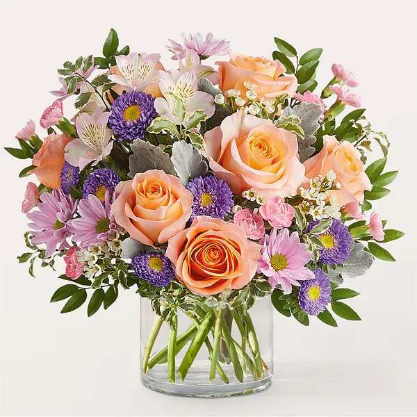 Glimmer Bouquet - Let this gift of stunning stems be a glimmer in their day, providing joy and light through soft, peach roses and lavender daisy poms.  Details The Premium Bouquet is approximately 15"H x 17"W. Designed by florists, ready to display. For long–lasting blooms, replace the water daily. We suggest trimming the stems every couple days. Pet Safety Precautions: This bouquet or plant may include flowers and foliage that are known to be toxic to pets. To keep them safe, be sure to keep this arrangement out of your pet's reach.