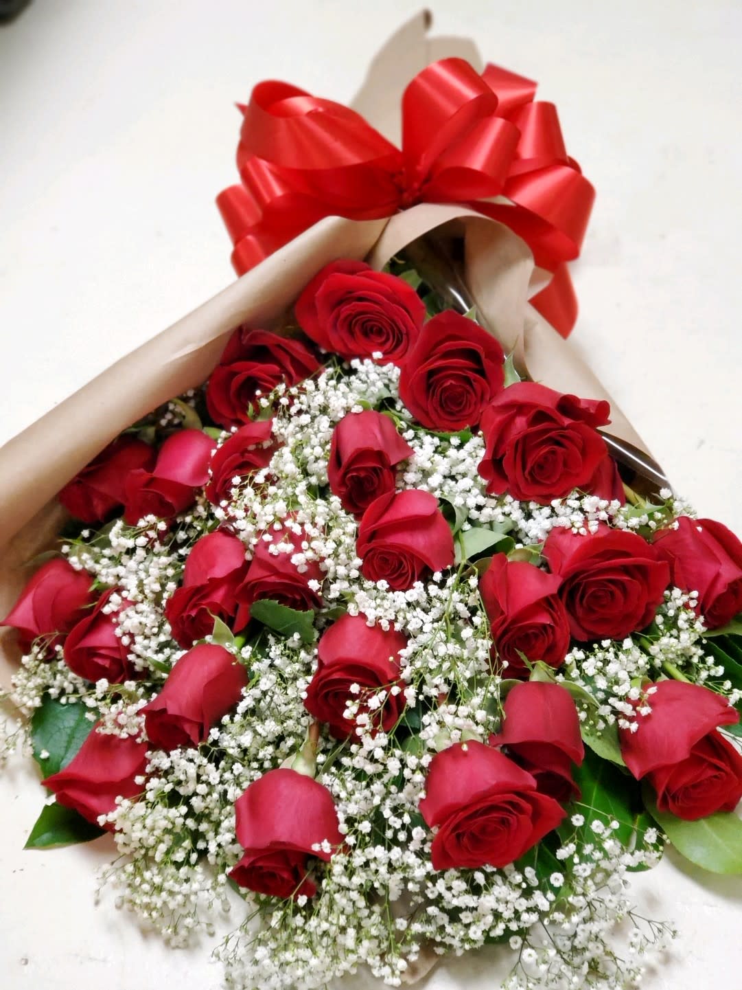 Two Dozen Roses Wrapped  - Two dozen roses wrapped in brown paper with greenery and filler 