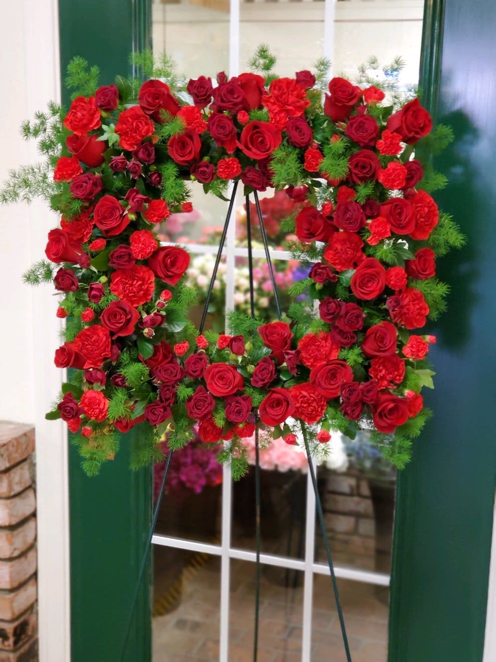 Square Wreath in Rich Reds  - Square wreath on an easel to include roses, spray roses, carnations, mini carnations and greenery 