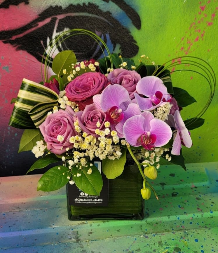 Purple Garden  - An arrangement in a clear vase with roses, orchids, fillers, and greenery 