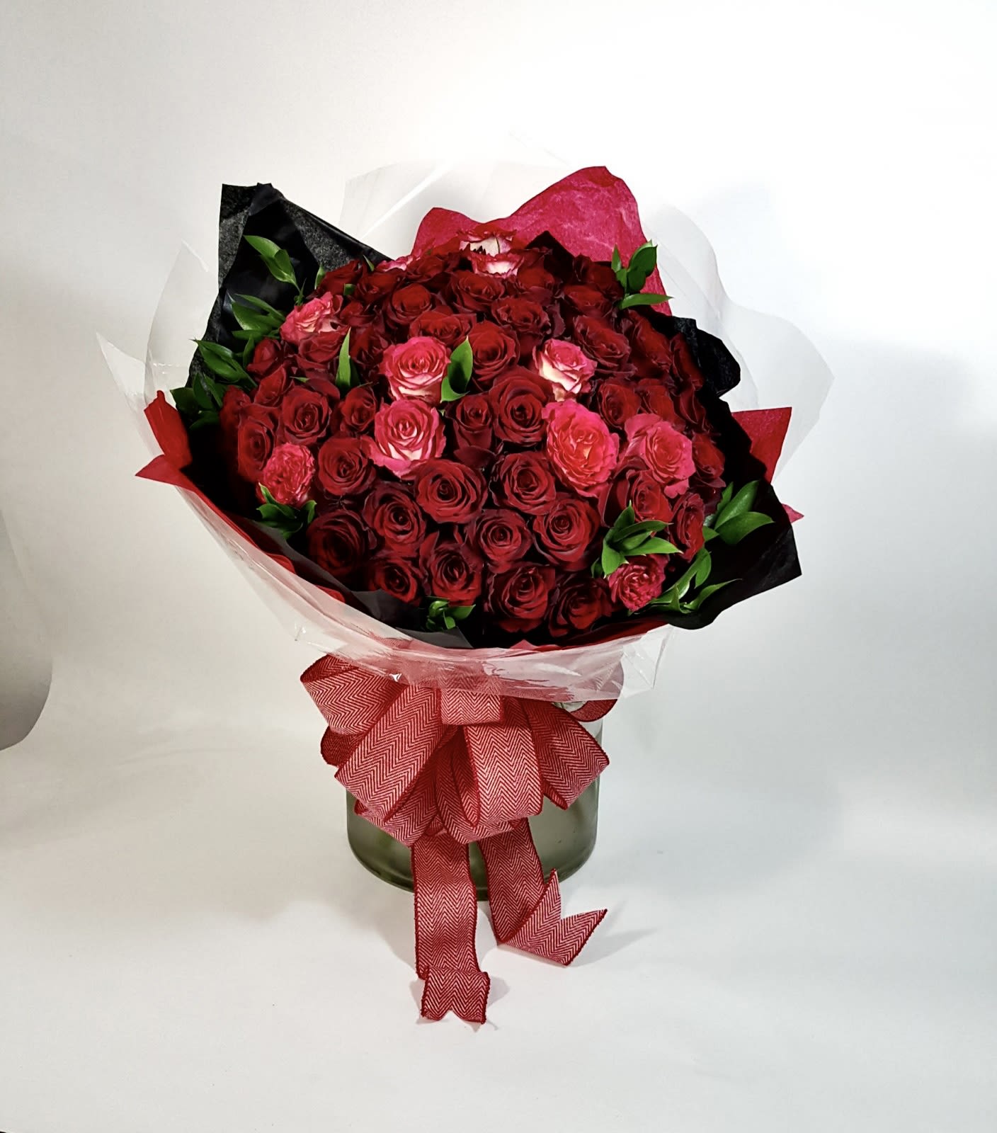 Romanza - Premium red roses bouquet with a bow and greens wrapped in premium paper  (Base not included)