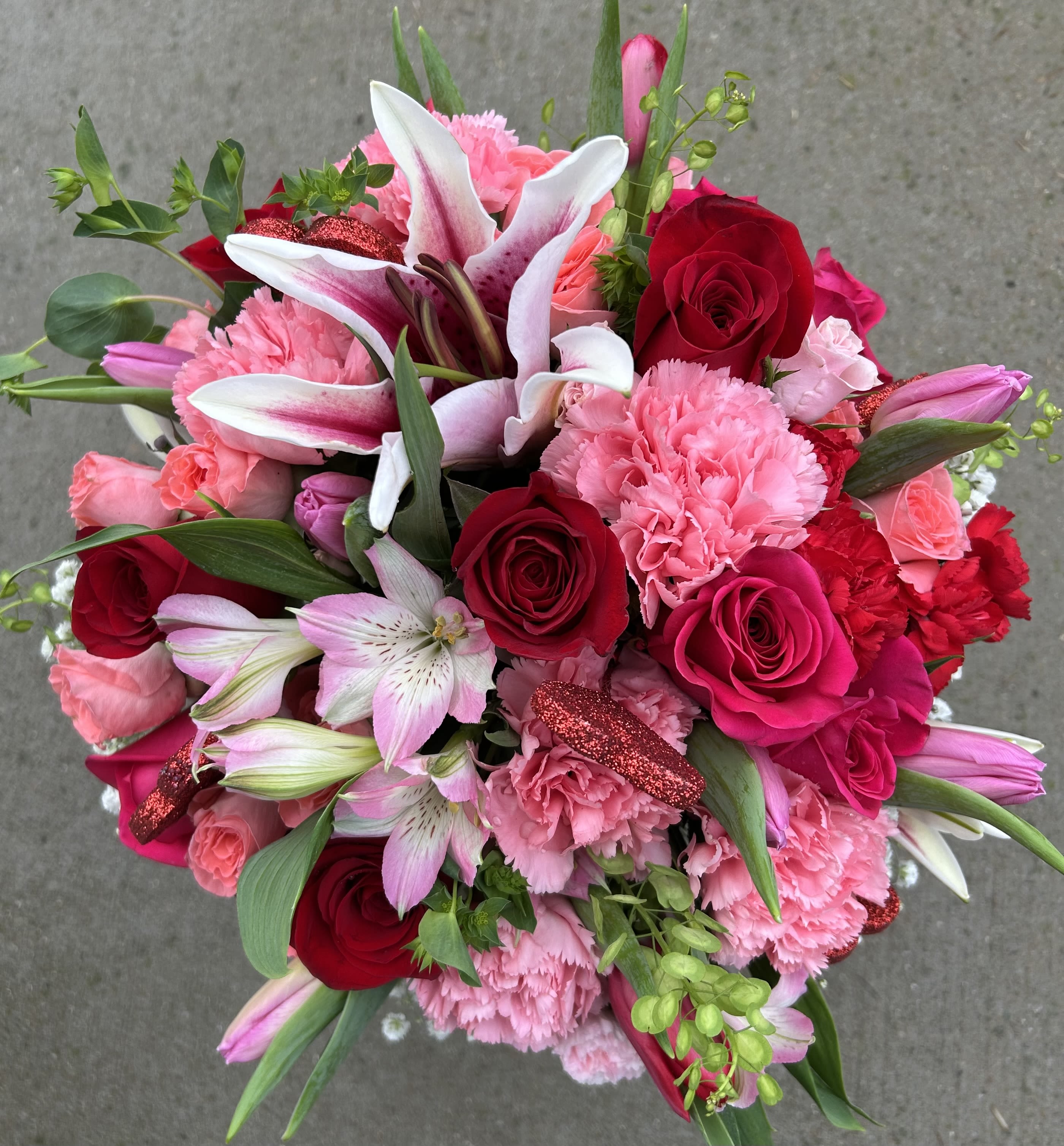 Sophia's Lily Rose Bouquet - A beautiful mix of Red Roses, Stargazer Lilies, Carnations and Alstroemerias with accent flowers placed in a gathering vase. This arrangement would  be a wonderful choice for Anniversaries, Valentine's Day or Just Because.