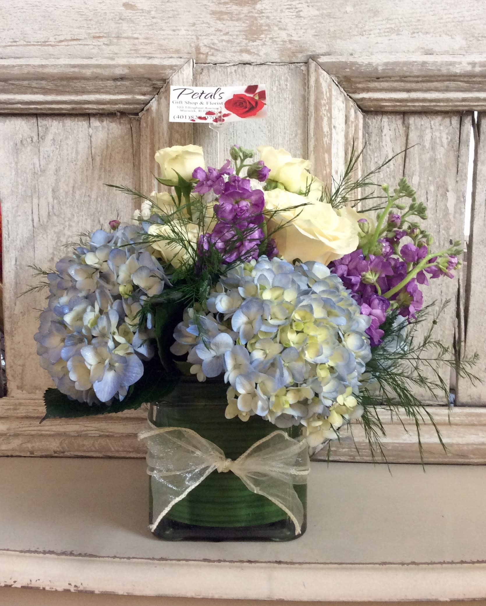 White Roses, Purple Stock and Blue Hydrangea Cube by Petals - Send a heartfelt message that truly stands out. Our exquisite design, featuring white roses, purple stock, and blue hydrangeas in a classic clear cube vase, is the perfect way to create a bright spot in a special someone’s day. [Please note: Flower varieties and shades may occasionally vary slightly based on daily availability.