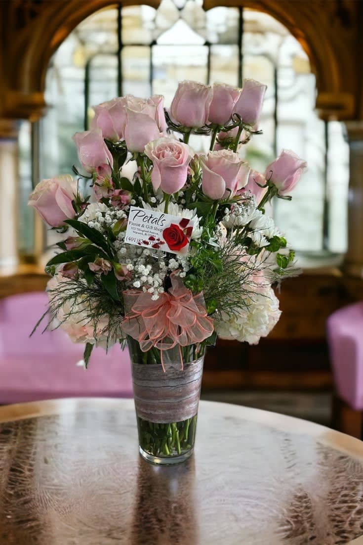 Blush Pink Dozen, Hydrangea with the Works ~ by Petals -  This stunning, tall arrangement is designed to impress your recipient. It features an 11-inch vase with a collar of light pink hydrangea, accented with white chrysanthemums, pink Peruvian lilies, and a dozen premium blush pink roses. Baby's breath and delicate tree fern complete the look, which is topped with a beautiful bow and includes your message card. Please note that the rose color may vary slightly due to availability.