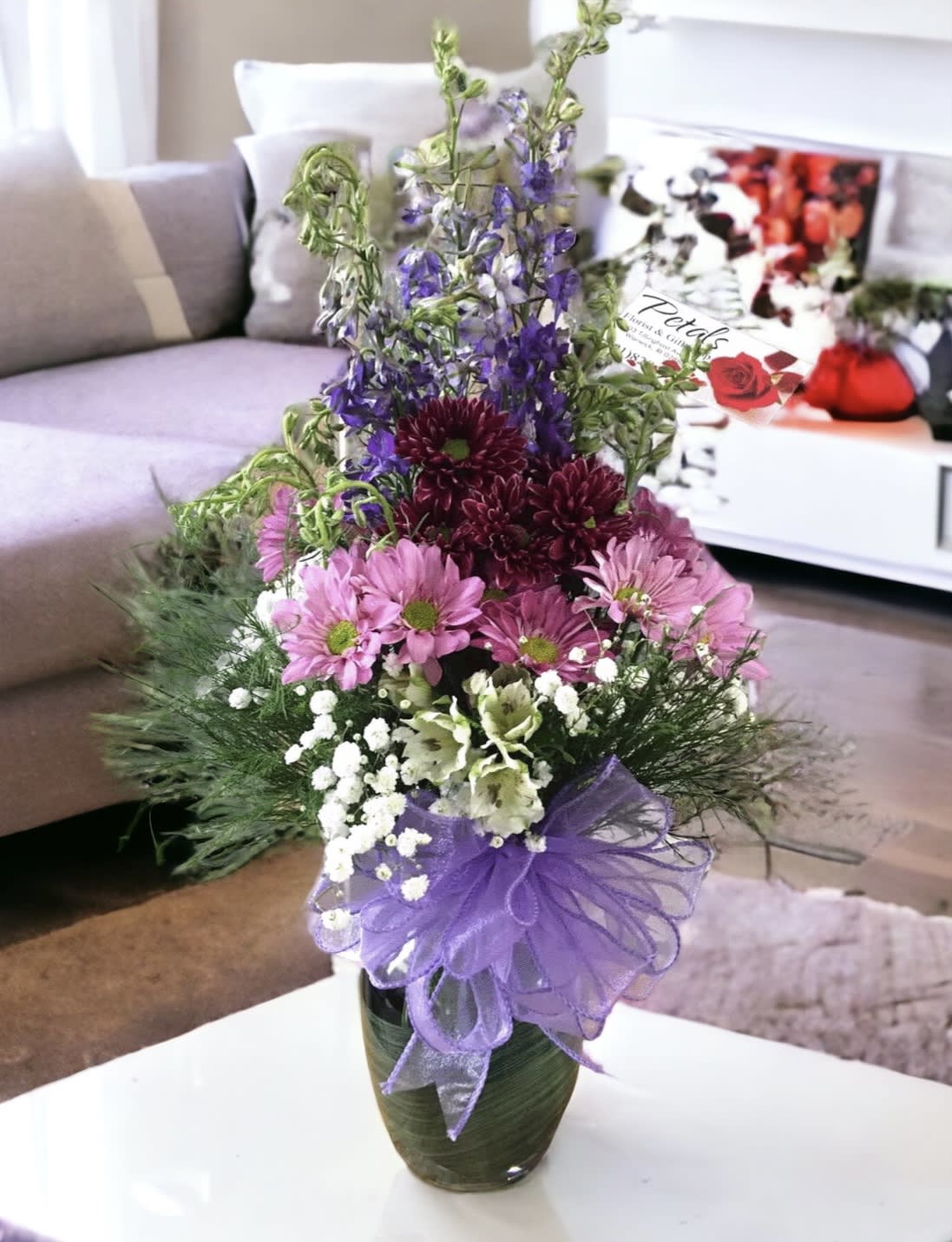 Precious in Purple Vase by Petals - If you want to impress someone and make them feel super special, a vase full of elegant, soft lavender flowers will do the trick.   This Precious in Purple design is so sweet...  this 6" glass vase is filled with a beautiful assortment of Lavender Larkspur,(or stock) long-lasting Alstroemeria, and Chrysanthemums in multiple shades of purple and soft lavender finished off with a pretty variety of filler flowers, greens, and a delicate lavender ribbon bow. On occasion, flower substitutes are made based on daily availability and season.  *Don't hesitate to contact me with any questions about this design. 401-828-0701  Thanks,  Cheryl