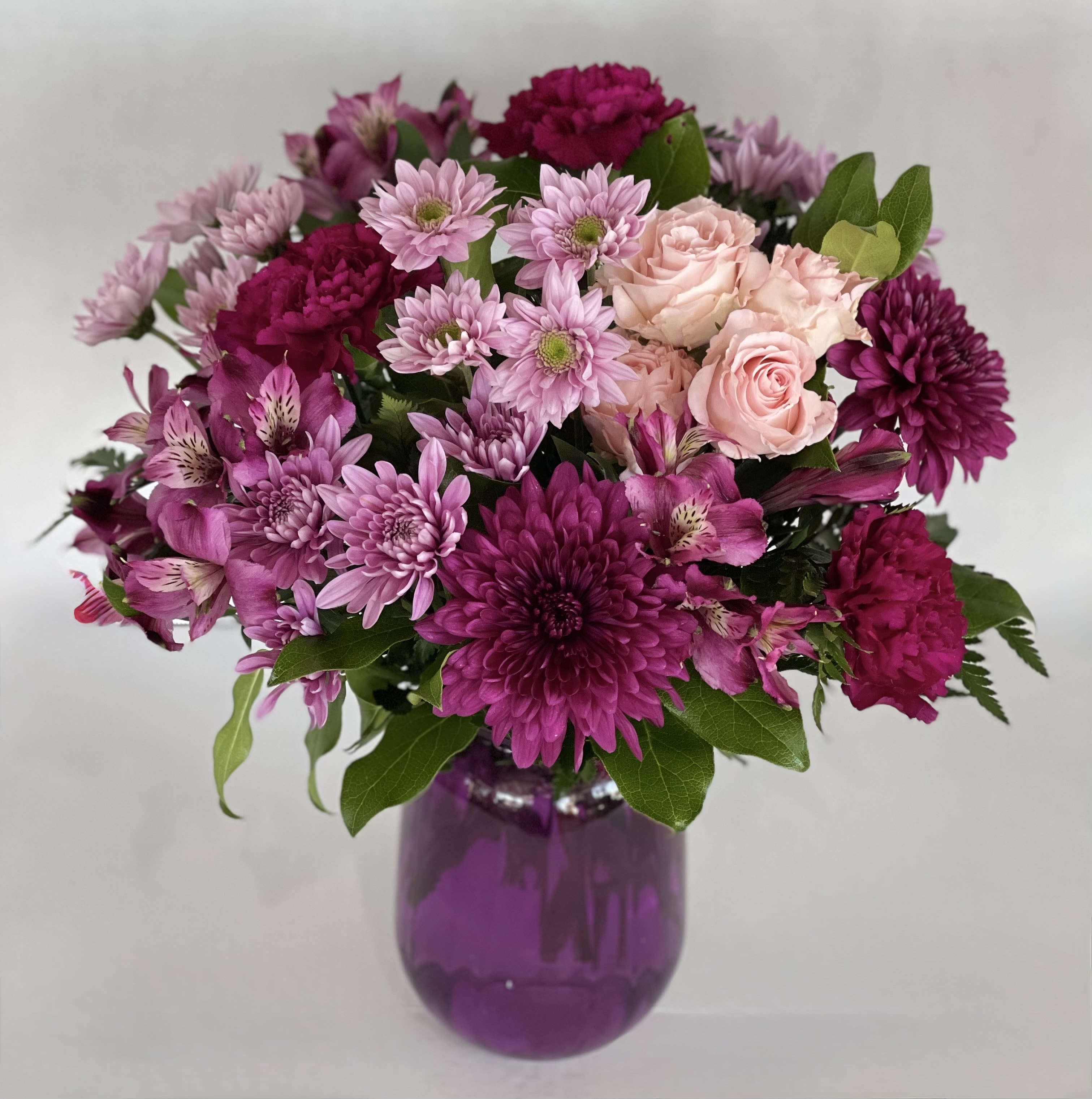 Purplexed - A playful array of bold purple and pink flowers including roses, daisies, alstroemeria and mums.