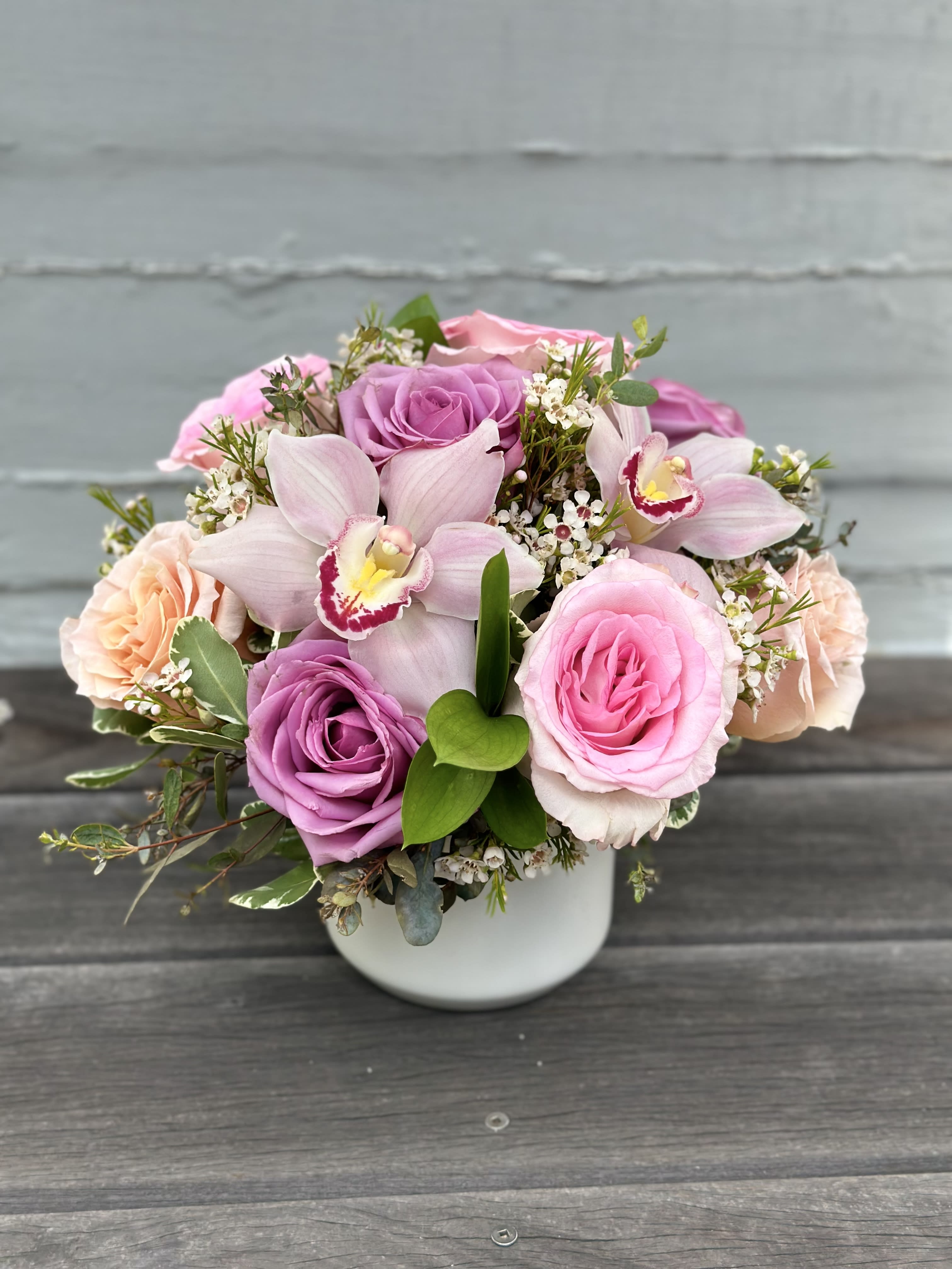 My Fair Lady - Understated elegance shines in this charming collection of 9 pastel roses, orchid blooms and seasonal foliage; designed to highlight the simple beauty that roses have to offer. Arranged in a keepsake ceramic pot. Cat and dog friendly flowers.