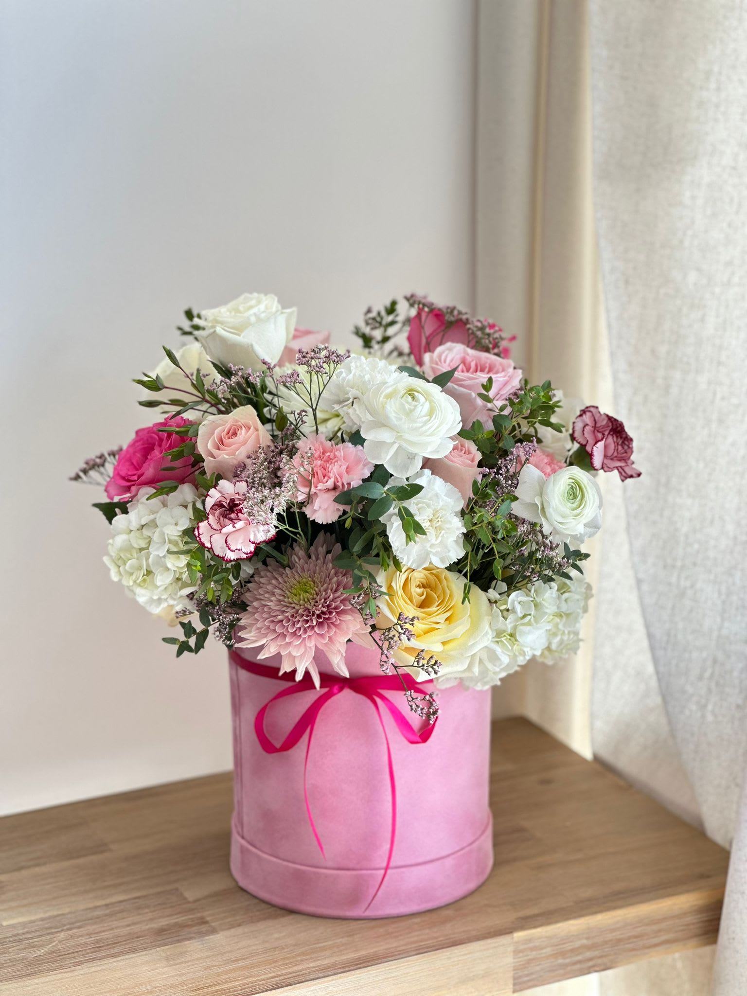 Hermosa  - A tall, round pink velvet box filled with pink, light pink, and white flowers.   Flower types may vary depending on the season.
