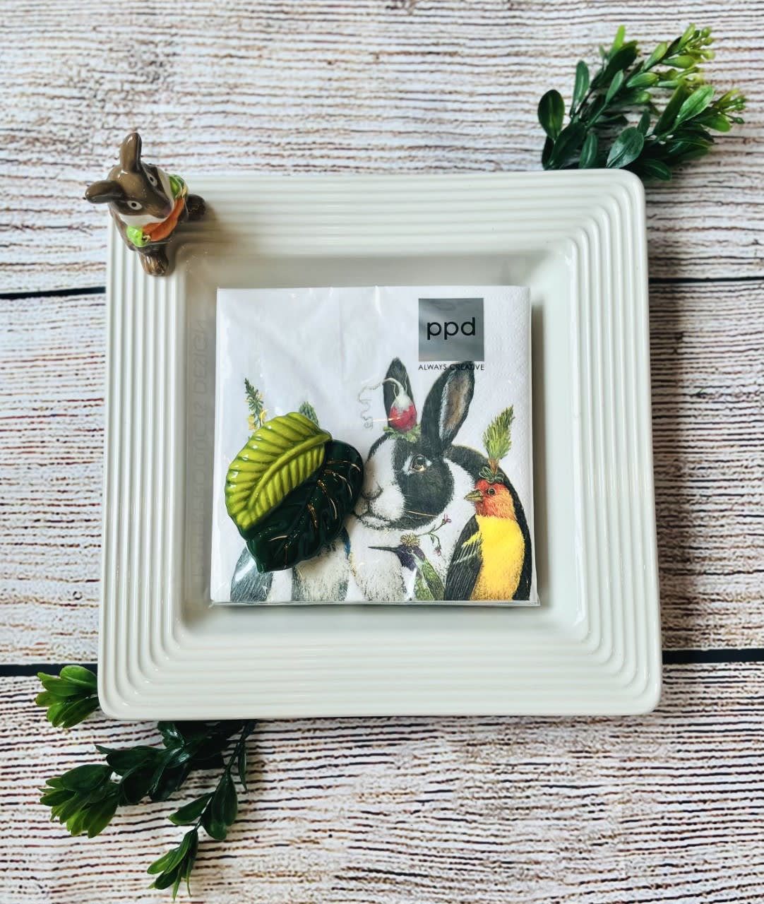 Nora Fleming Napkin/Candy Dish with 2 "Mini" Decorations - This charming dish holds cocktail napkins, nuts, or candy and makes a sweet addition to anyone's Nora Fleming collection. It comes with 2 interchangeable toppers. Standard $70.00 Deluxe $80.00 (Includes 3 toppers) Premium $100 (Includes 5 toppers)