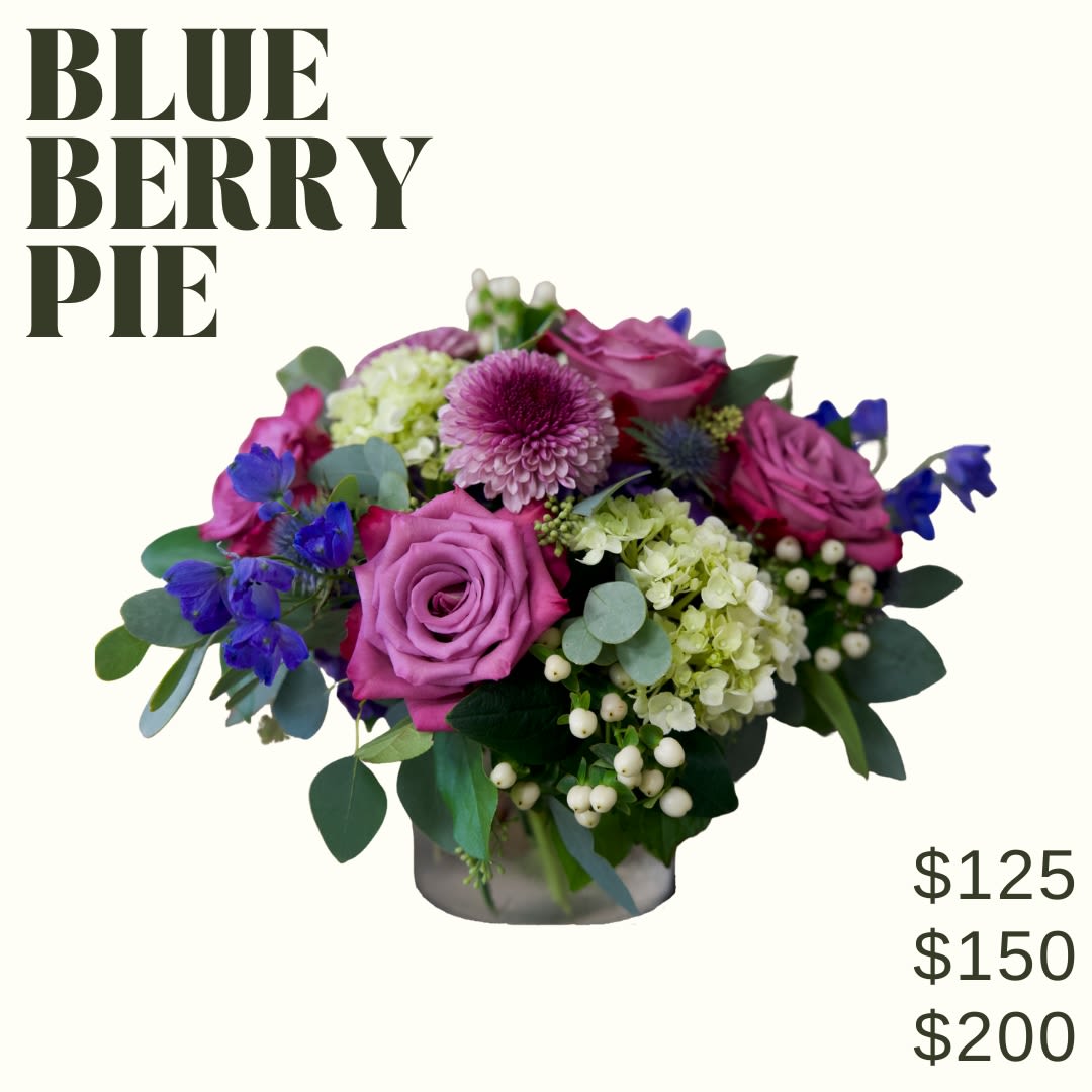 BLUEBERRY PIE  - Blueberry pie is a low and lush bouquet artfully designed in a clear glass cylindrical vase using rich purple and blue tones!   *Image shown is valued at $125 *The $150 and $200 price points will be made fuller and more luxurious by adding additional blooms in the same color palette  