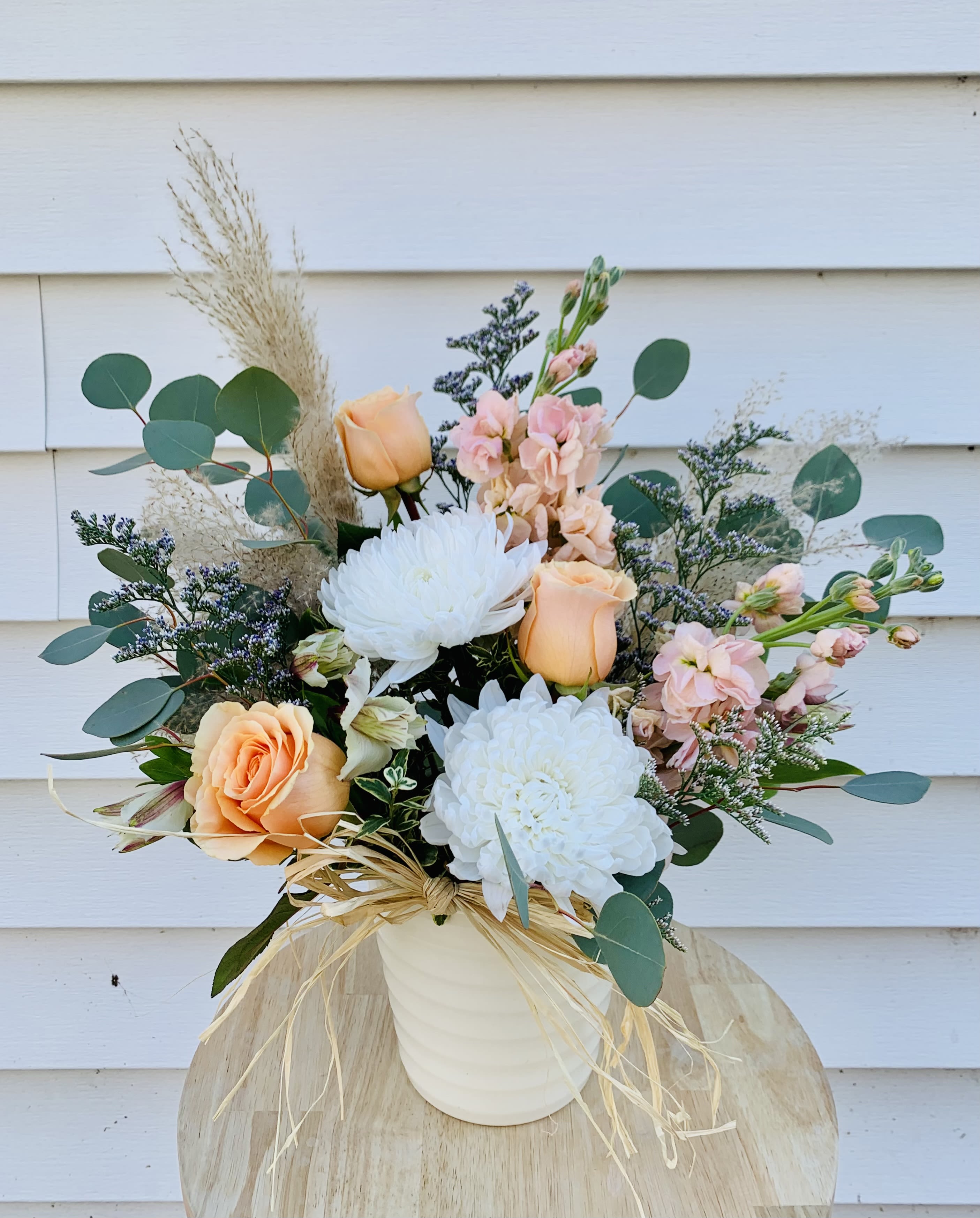 Boho Babe Arrangement - Indulge in the carefree essence of Bohemian style with the Boho Babe arrangement. Featuring Pompas plumes, dancing silver eucalyptus, and long-lasting white mums and blooms of soft peach hues, this floral masterpiece embodies a boho-chic vibe that will elevate any space with its natural beauty.