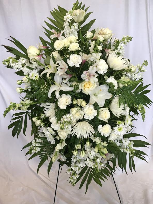 Sentiments of Serenity Spray - Beautifully simple, this lovely spray of white roses, lilies and carnations decorated with white satin ribbon is a tasteful way to express your sympathy. 