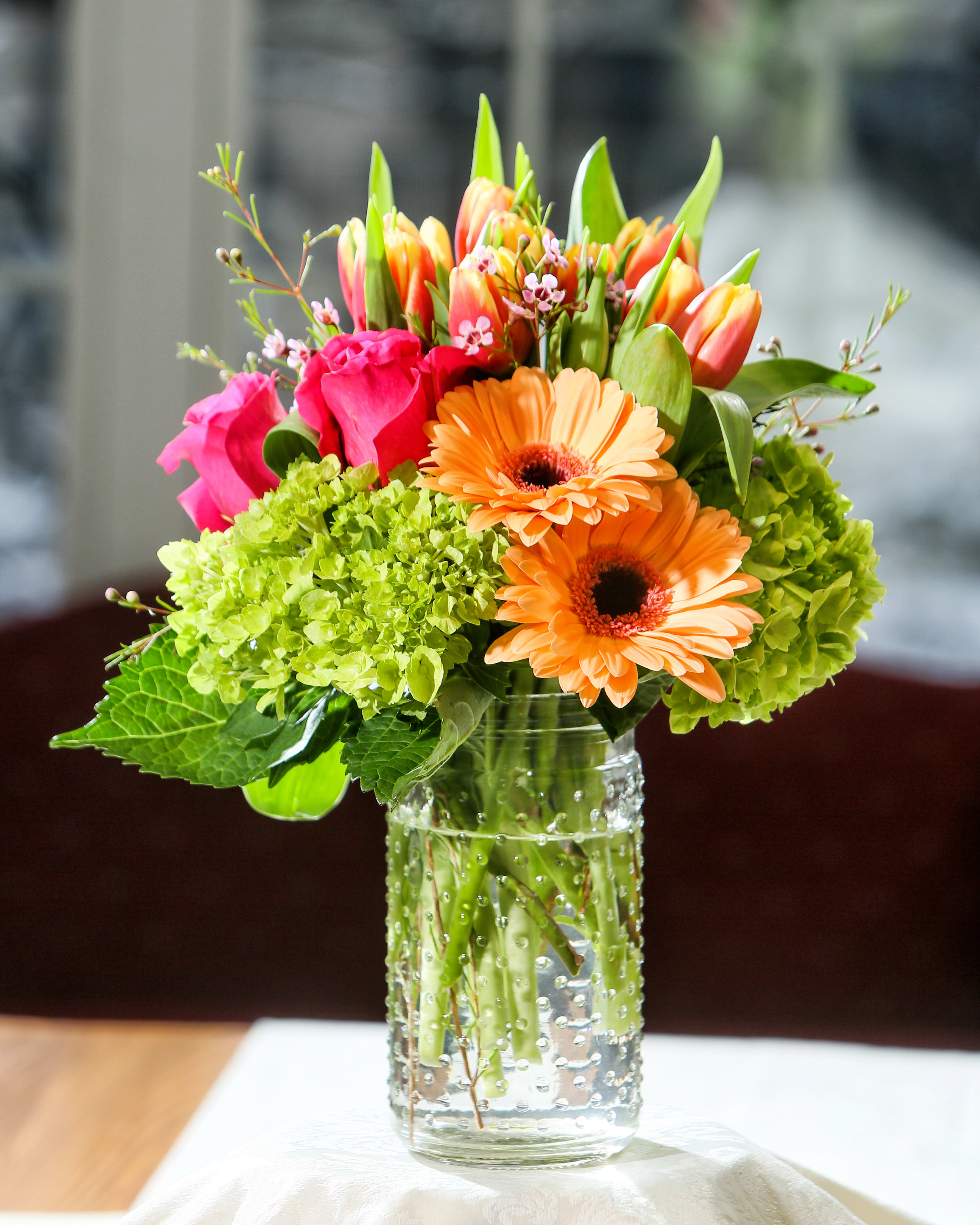 Spring It Up Bouquet - LOCAL DELIVERY ONLY!!! (Salem, Windham, Derry, Londonderr, Hampstead, Atkinson, Methuen, Andover, North Andover, Lawrence &amp; Haverhill) Bright mix of fresh flowers to include tulips, hydrangea, gerbera daisy's. roses and wax flowers.  Designed in a clear glass hobb nail vase. Flowers and Colors may vary! Local delivery ONLY please! 