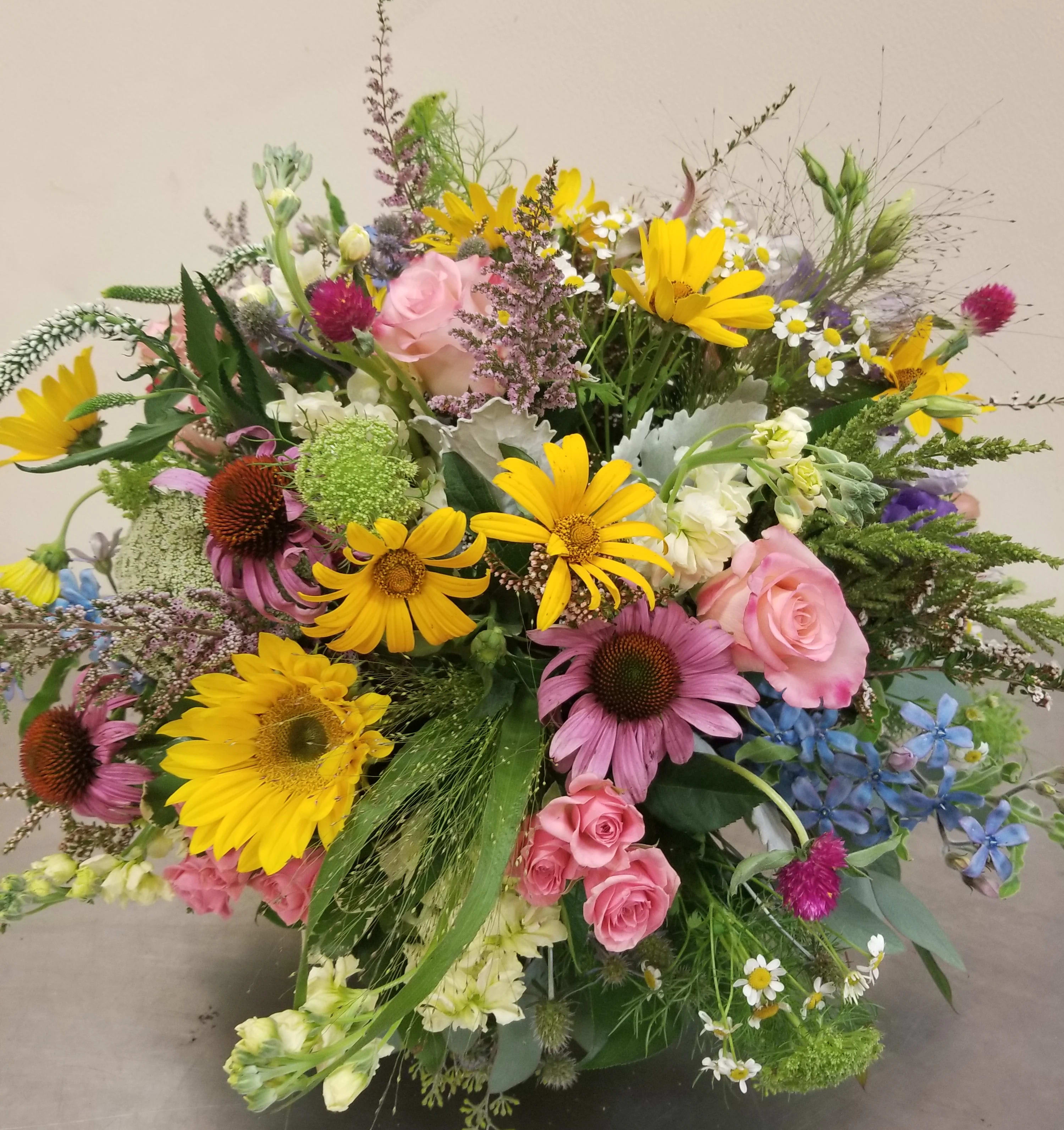 "Butterfly Garden" Bouquet - This charming bouquet of wildflowers looks as though a summer meadow has been delivered right to the front door!  An assortment of blooms. Flowers may include roses, rudbeckia, Queen Anne's Lace, heather, and sunflowers. This bouquet may attract more than just butterflies. Flower varieties may vary. We love to showcase our local growers' blooms in this bouquet. So, the selection is always changing through the season! 