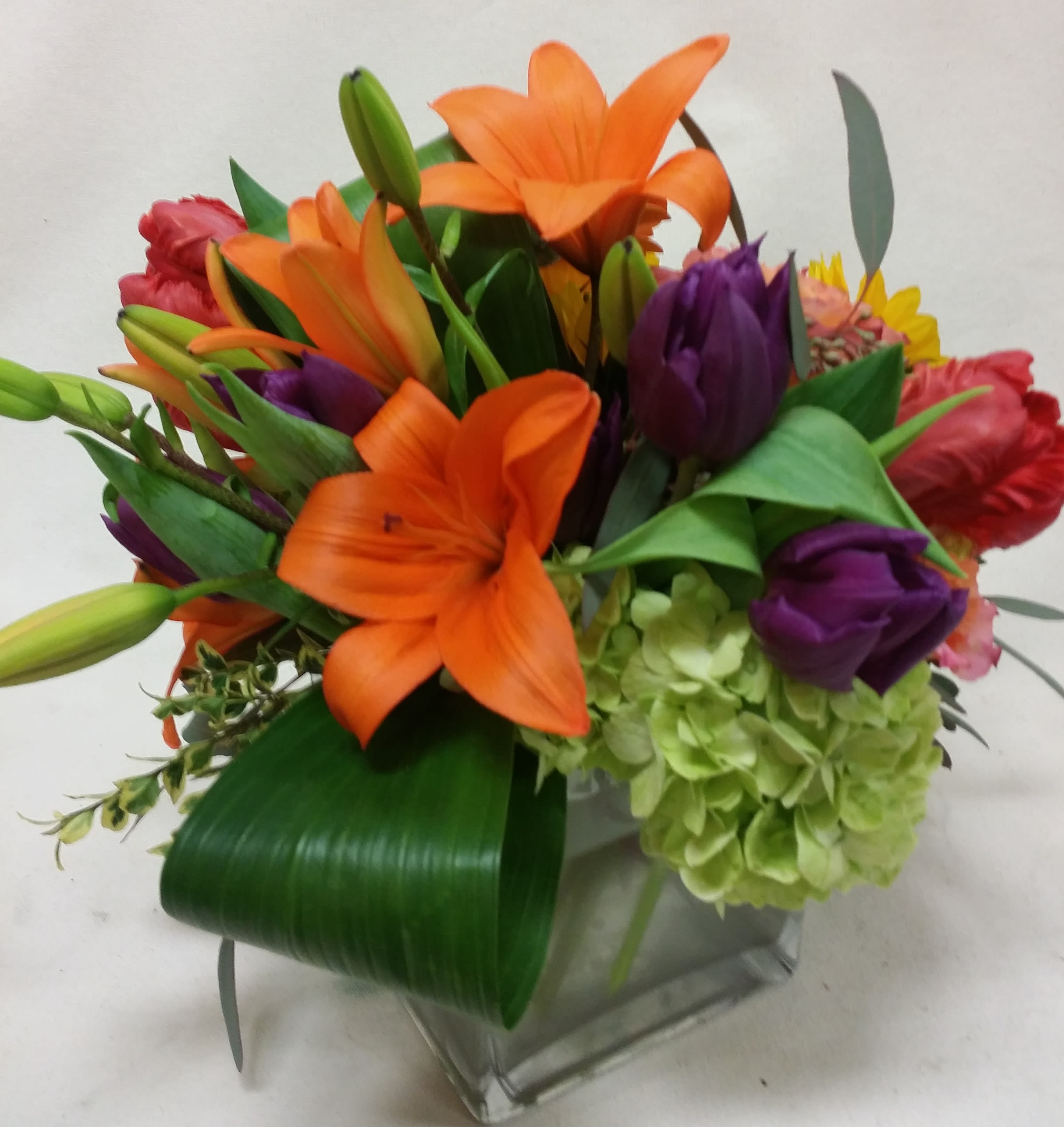 Bright Attraction Bouquet  - Vibrant orange lilies and purple tulips stand out against green hydrangeas and distinctive foliage.  Great for making an impact!