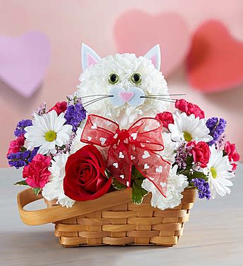 Flirty Feline - We’ve created the purr-fect surprise for someone special! Handcrafted from fresh white carnations, our cute cat arrives in a charming basket filled with a mix of hot pink mini carnations, white daisy poms and more. Holding a single romantic red rose and finished off with a sweet bow, our truly original kitten is sure to have everyone smitten!  Our florists hand-design each arrangement, so colors and varieties may vary due to local availability One-sided arrangement of white carnations, a red rose, white daisy poms, hot pink mini carnations, pink limonium, purple statice and variegated pittosporum; accented with a decorative ribbon Crafted in the shape of a cat, complete with ears, eyes and mouth with whiskers Artistically designed in a lined splitwood basket with handle