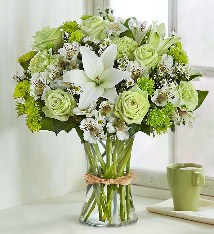 Serene Green - Bring some calm to someone special in your life. Inspired by the beauty of nature, our subtle, charming arrangement is hand-designed with the freshest blooms in delicate shades of green and white, arranged in a classic gathering vase tied with raffia. Just one look will have them smiling and will reflect your thoughtfulness!  Our florists hand-design each arrangement, so colors, varieties and container may vary due to local availability Arrangement of roses, carnations, lilies, alstroemeria, athos poms, monte casino salal and gypsophila, all in shades of green and white Artistically designed in an 8"H clear glass gathering vase accented with hand-tied raffia Lilies and alstroemeria may arrive in bud form and will open to full beauty in 2-3 days