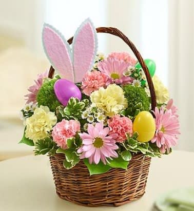 The Easter Bunny Basket - Send Easter smiles by the basketful! We have taken the prettiest blooms in pastel shades of pink, yellow and purple, and gathered them together inside a rustic handled basket. Then we got a little playful by adding a pair of bunny ears and colorful Easter eggs. Whether you are sending this charming bouquet as a gift for the holiday hostess, or making it the centerpiece at your own celebration, this truly original gift will have everyone hopping with delight!  Colorful Easter arrangement of pink roses, green trick, carnations, mini carnations, poms and monte casino, gathered with variegated pittosporum and salal Features a pair of pink felt bunny ears and colorful plastic Easter eggs Hand-designed in a handled willow basket; measures 8"H Large arrangement measures approximately 12"H x 12"L Medium arrangement measures approximately 10"H x 11"L Small arrangement does not include roses; measures approximately 9"H x 10"L Picked at the peak of perfection delivered fresh to their door
