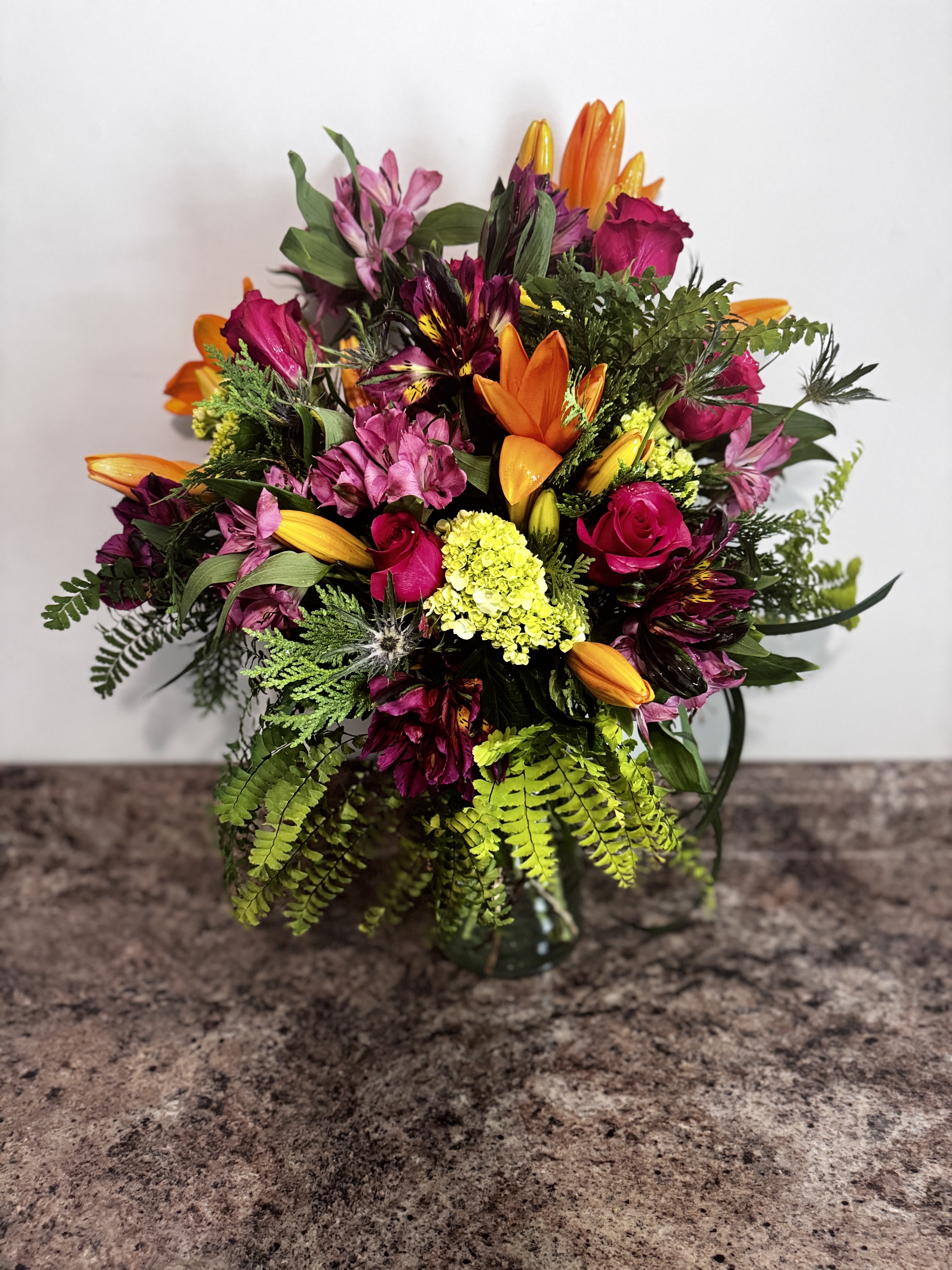 Spice up the day - A gorgeous array of color with stunning stems from lilies, rose, alstronova, thistle and even umbrella fern.
