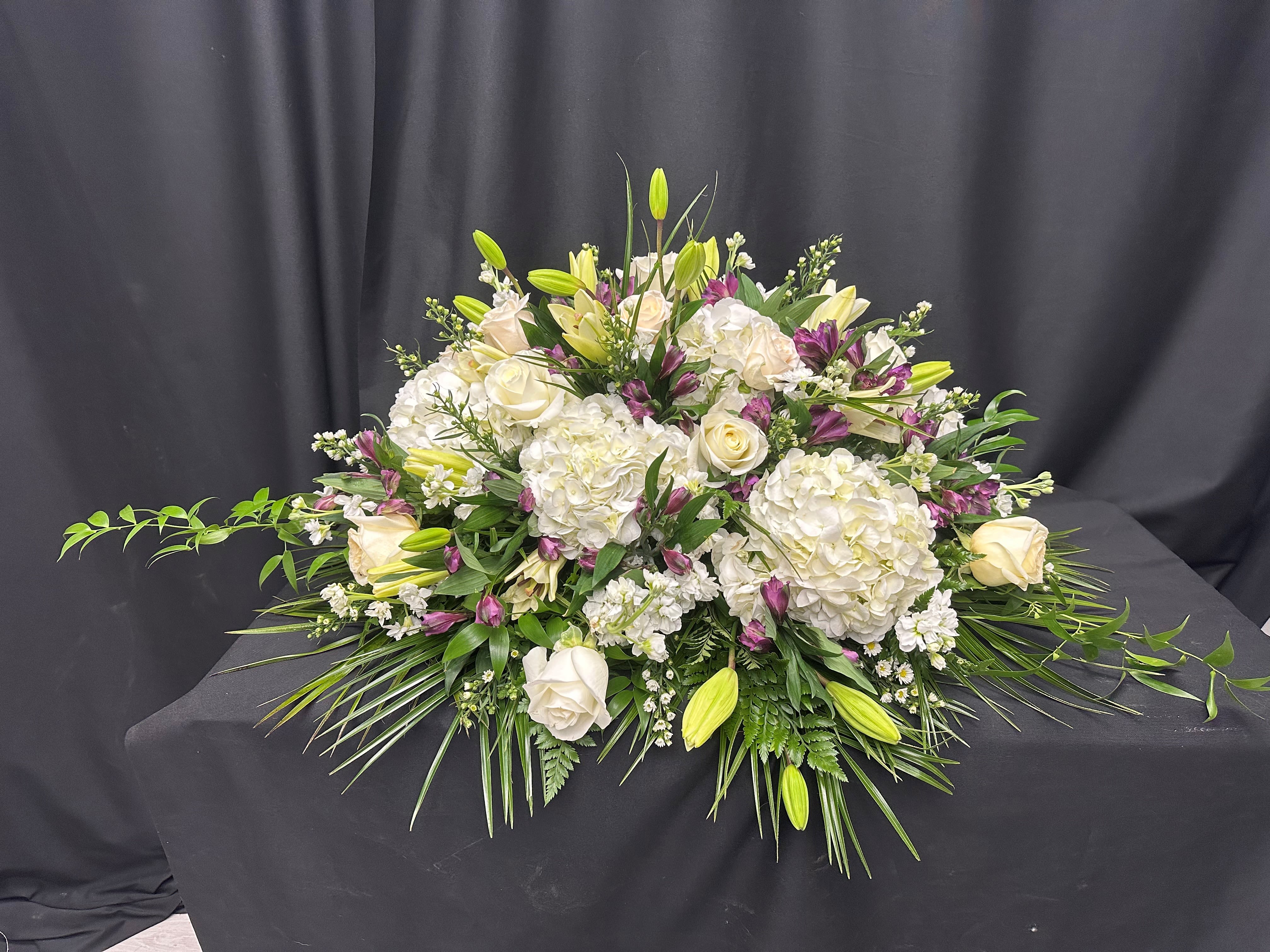 Eternal Grace - Honor a life well-lived with the "Eternal Grace" casket spray, a timeless expression of love and remembrance. This elegant arrangement features lush white hydrangeas, classic roses, and delicate lilies, accented by deep purple blooms and verdant greenery. Designed to bring comfort and beauty, it serves as a heartfelt tribute to celebrate cherished memories.