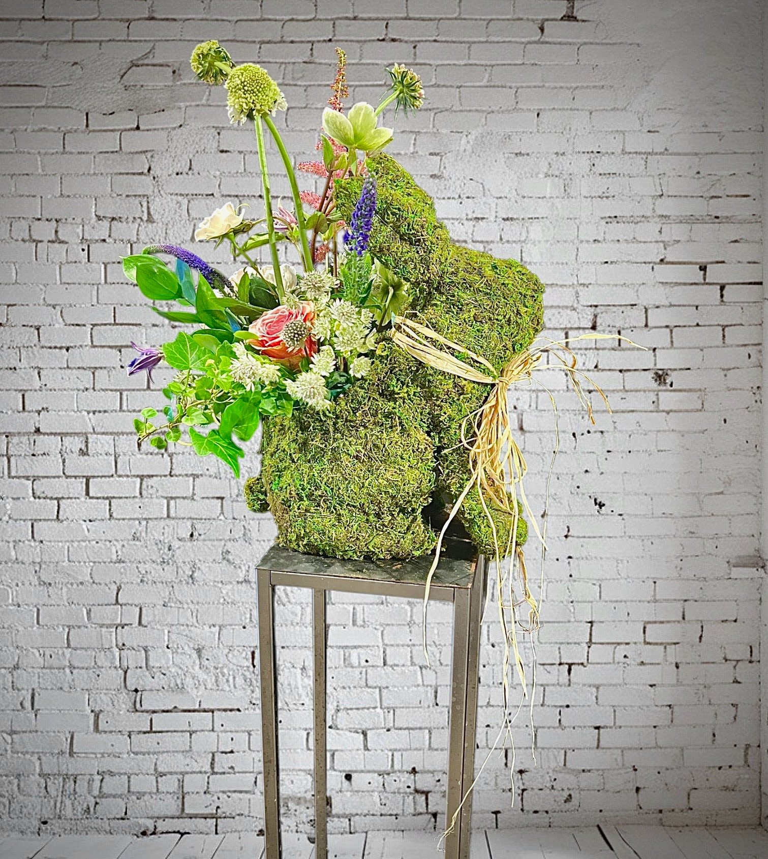 Moss Bunny and wildflowers - Nothing heralds the coming of Spring quite like a bunny!  And this creation features random and beautiful assortment of small blooms all gathered together and place in a moss topiary bunny form.  The bunny is approx 15x10x6 and some flowers hover above that
