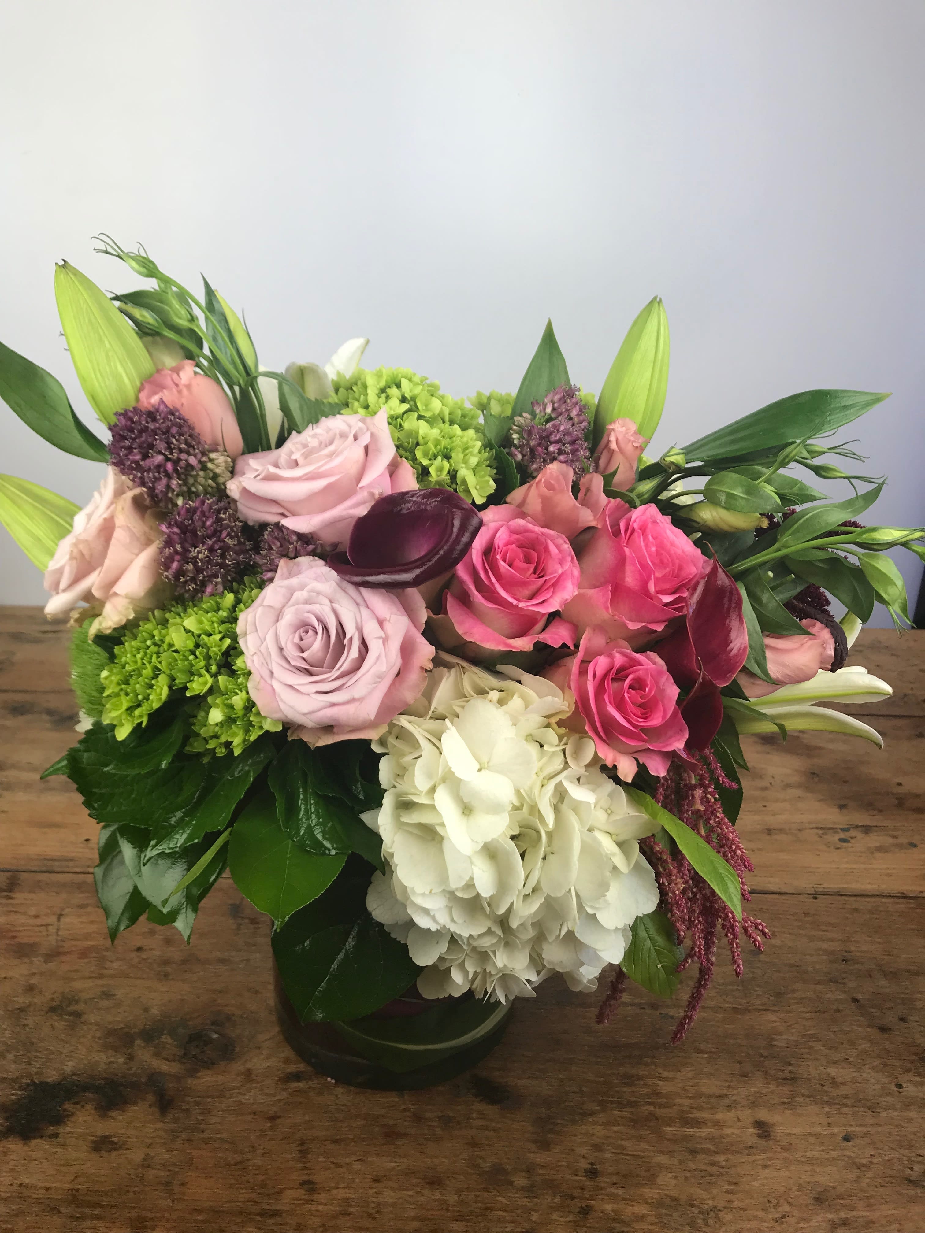 English Garden - A charming French-style arrangement featuring a delicate mix of garden roses, lush hydrangeas, soft lisianthus, and more, creating a timeless, romantic feel. This elegant design captures the beauty of a classic garden, perfect for adding a touch of Parisian charm to any occasion.