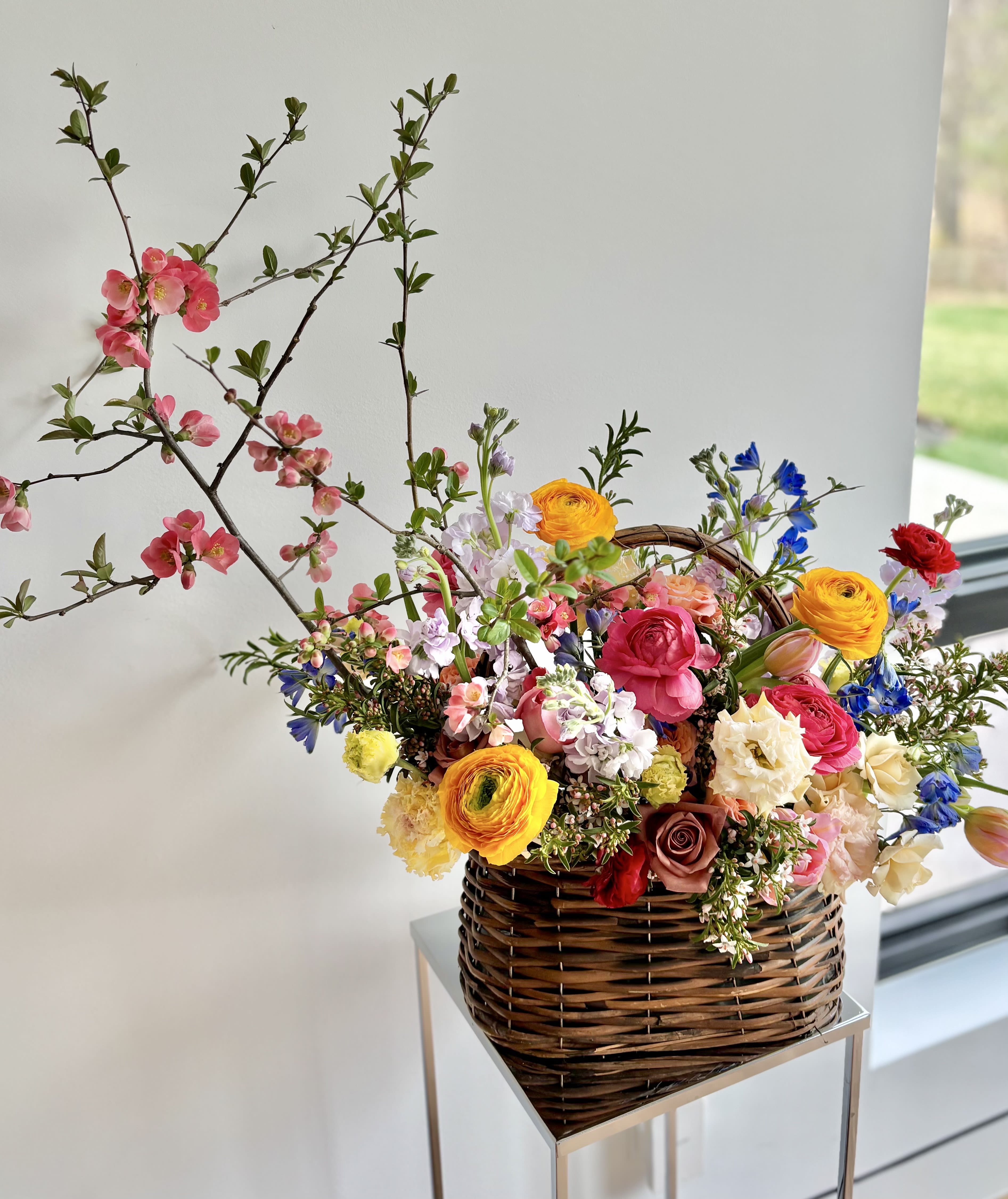 Flowering Basket - Large - Woven basket filled with premium flowers to celebrate this season - a perfect seasonal flower gift to decorate your or your loved one's home. Mix of premium colorful flowers carefully selected by designer to make a stunning arrangement. Mix of roses and spray roses, ranunculus, tulips, lisianthus, stock, delphinium, peonies and daffodils (when in season) and more, with flowering branches when available. 