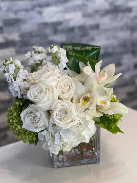 Timeless - A sophisticated compact arrangement featuring white and green hydrangeas, fragrant stock, delicate lisianthus, elegant cymbidium orchids, and pristine white garden roses. This carefully curated design radiates elegance and freshness, perfect for any occasion.  